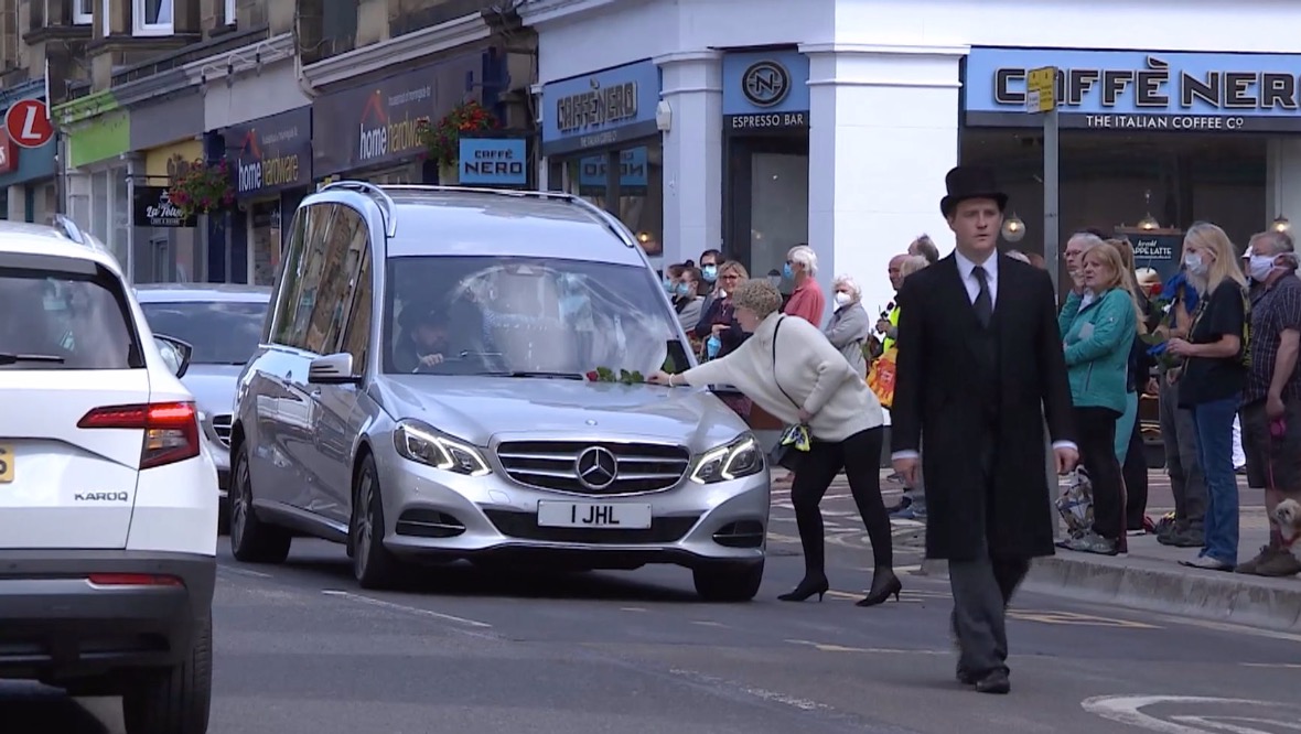 Funeral cortege: Mourners placed roses on the hearse as it passed.