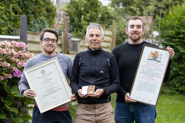 David Brunton’s son Jamie with his sons holding the bravery medal and certificates.