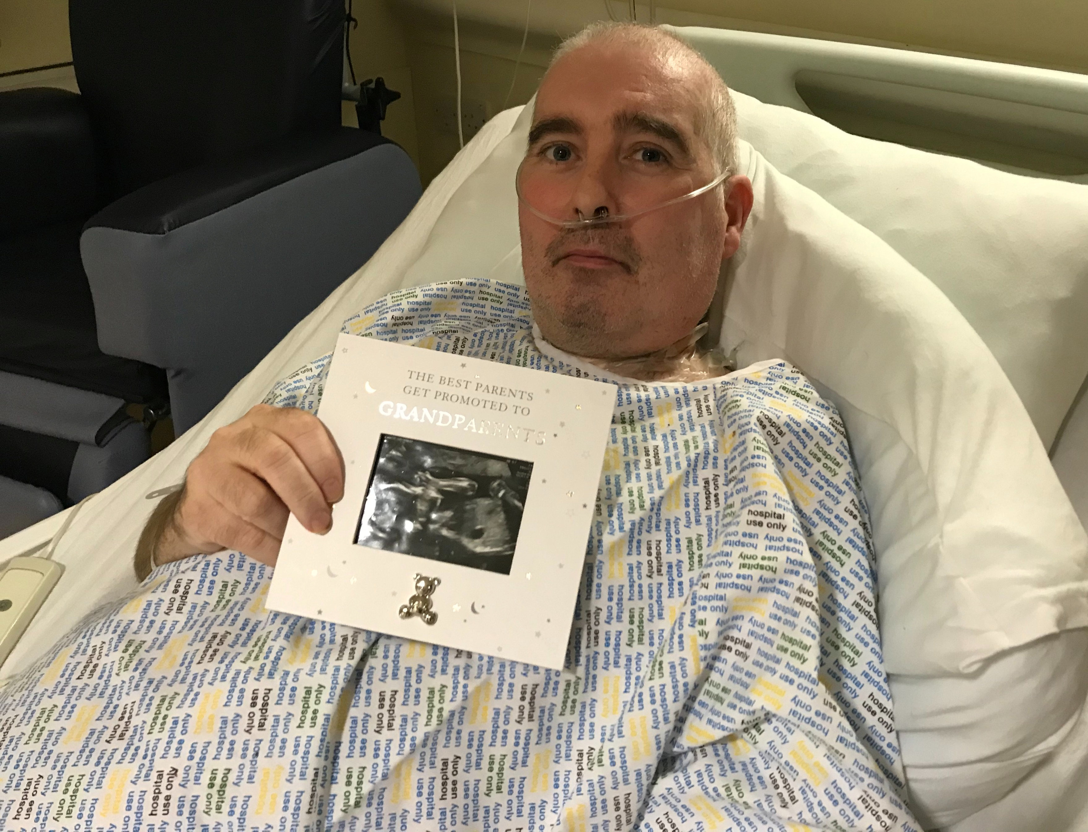 Brian Fernie holding a card with his daughter's baby scan.