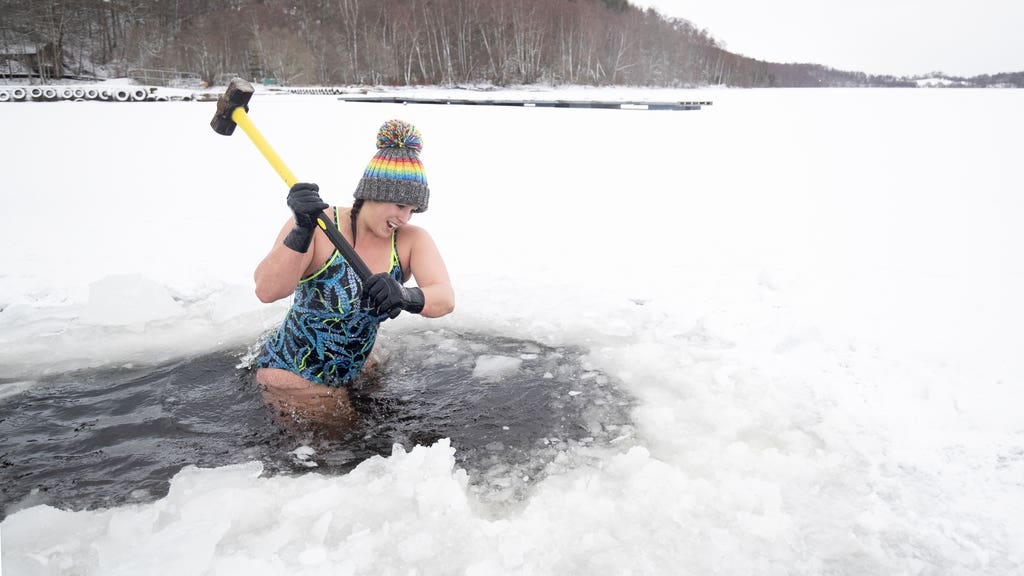 Outdoor swimmer uses sledgehammer to break up frozen loch