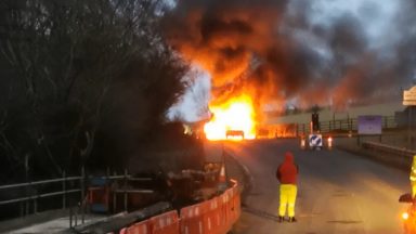 Two cars burst into flames after collision blocking road