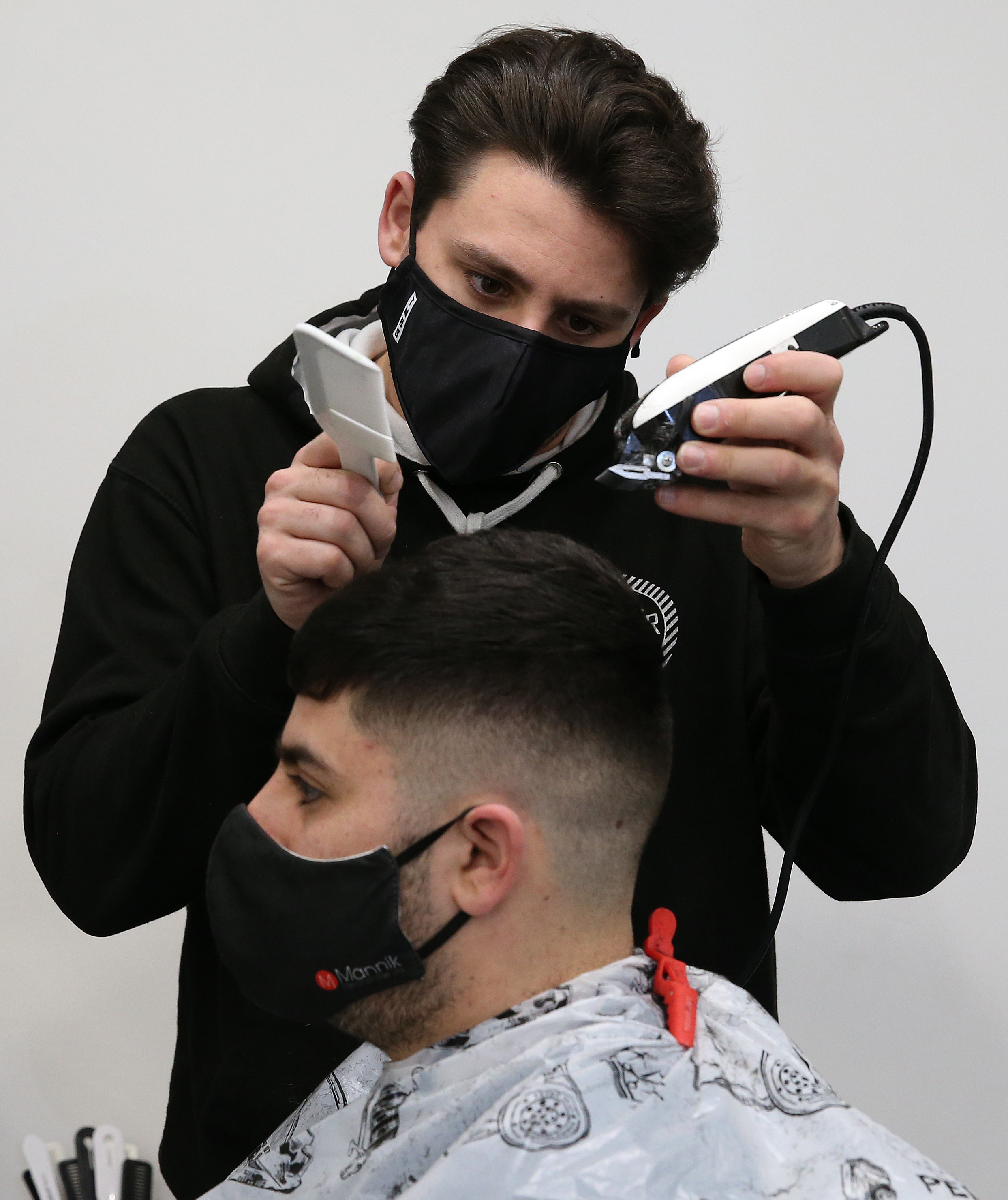 Barber Tony Mann trims his brother Maxx's hair after his shop reopened.