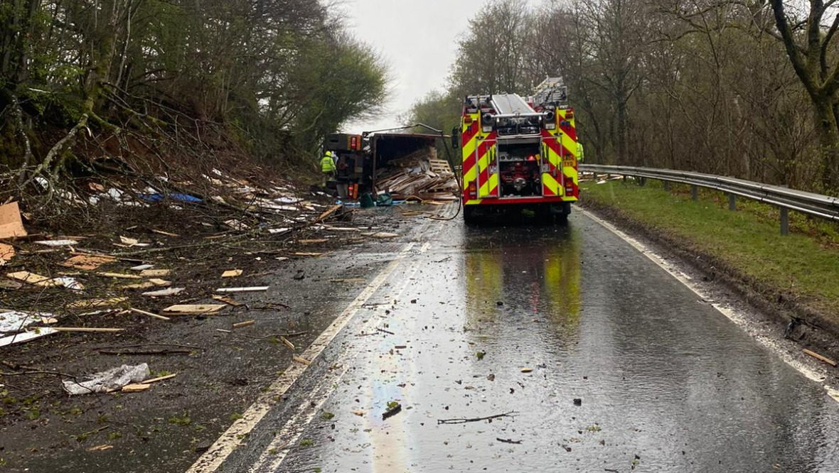 Road closed and woman taken to hospital after lorry overturns