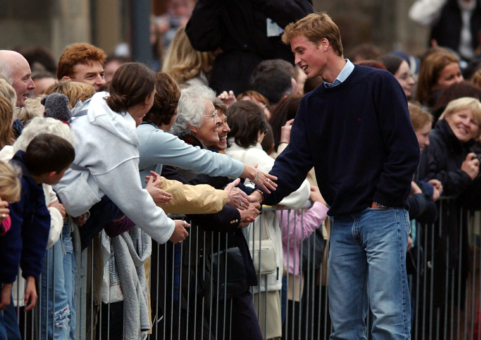 William shakes hands with a wellwisher as crowds gathered to witness his arrival at university in 2001 (PA)