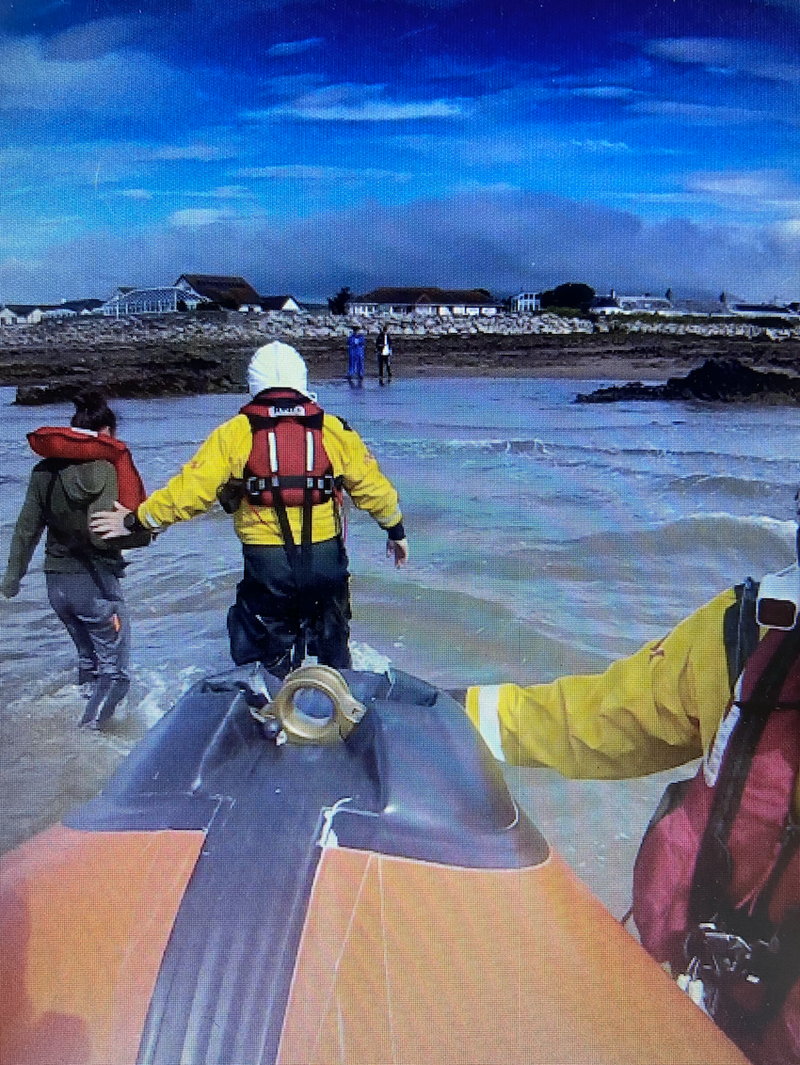 A crew member walks with the casualty to shore.