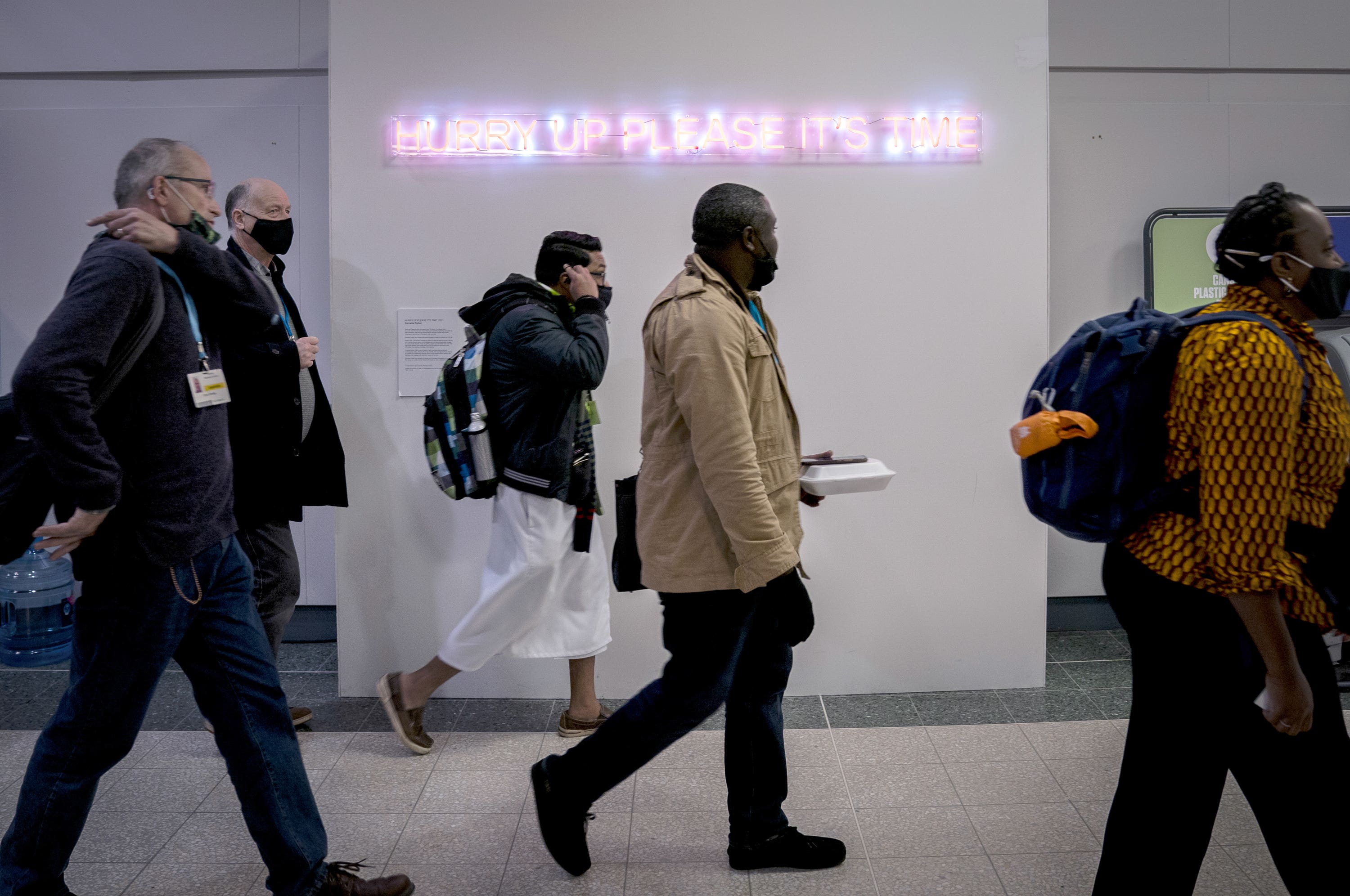 Delegates walk past the neon light installation ‘Hurry Up Please It’s Time’ by artist Cornelia Parker during the COP26 summit.