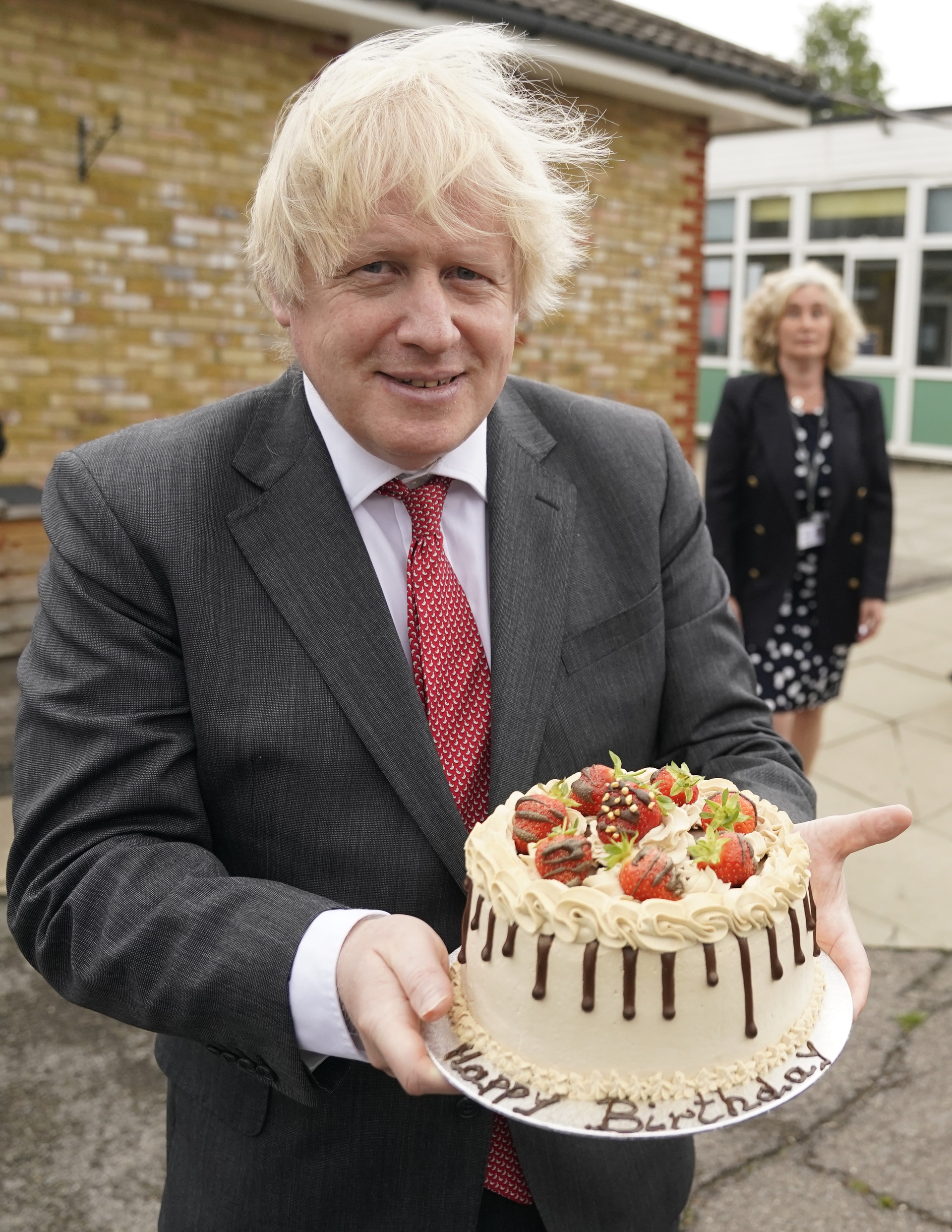 The Prime Minister Boris Johnson holds up his birthday cake as he visits Bovingdon Primary Academy, the cake was made by the staff at Bovingdon Primary Academy in Hemel Hempstead during Covid-19.