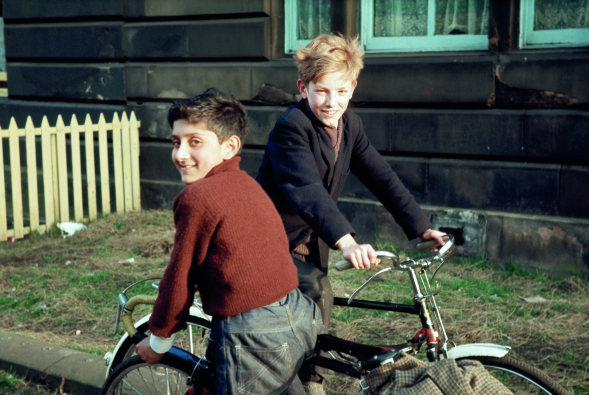 Two boys with bikes outside a tenement building.