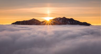 Peaks of Highland mountain range pictured poking through clouds at sunset