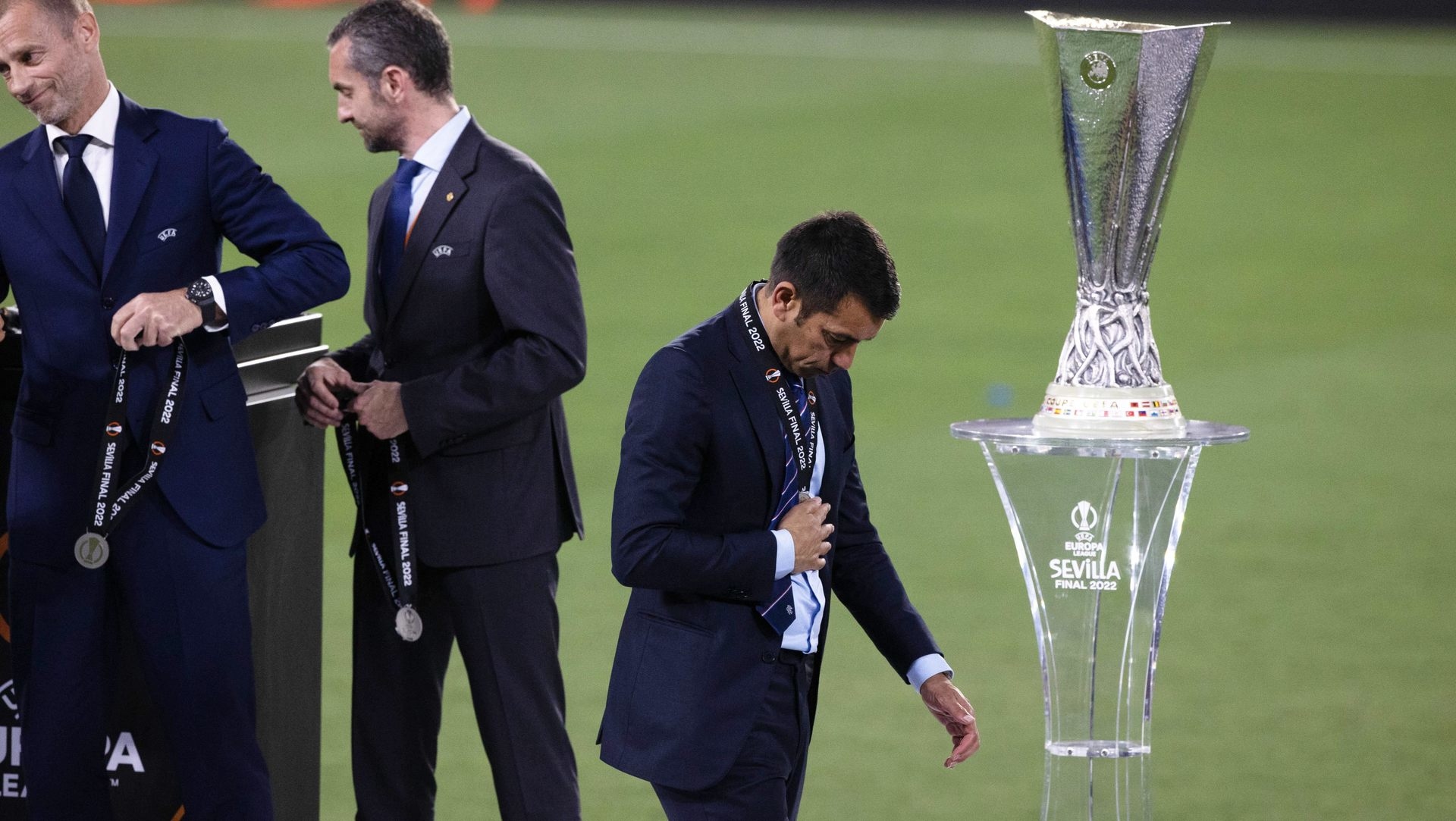 Giovanni van Bronckhorst walks past the Europa League trophy after penalty shootout defeat.