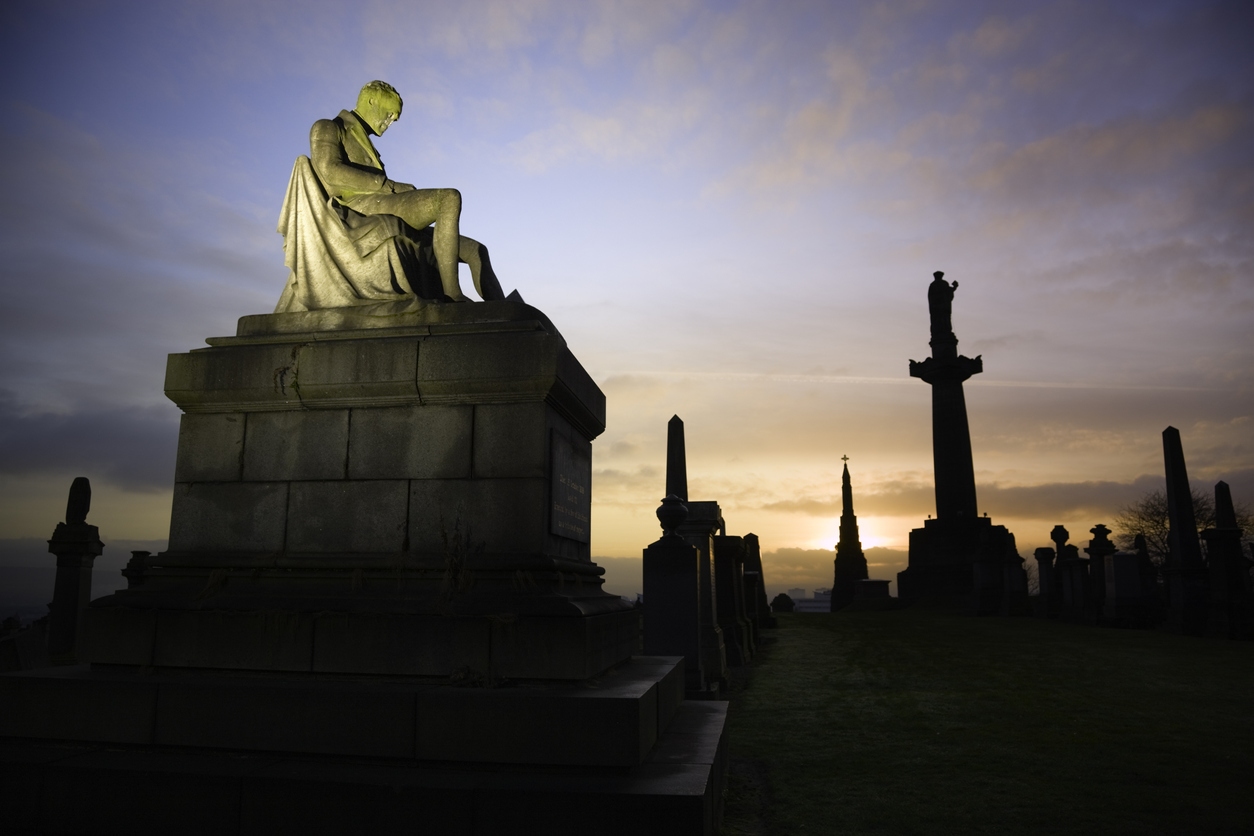 Victorian tombs and monuments in Glasgow's Necropolis cemetery at sunset.