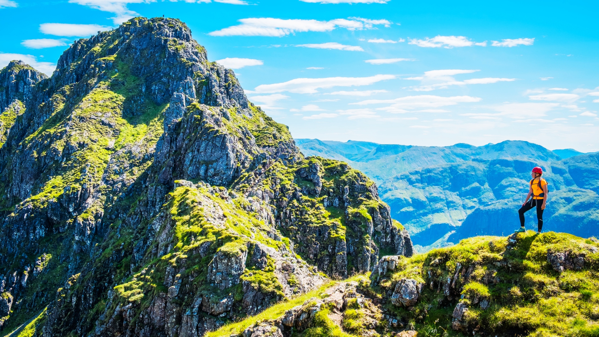 Mountaineer looking along the peaks of the Aonach Eagach ridge, the dramatic rocky trail high above Glen Coe deep in the mountain Highlands of Scotland.