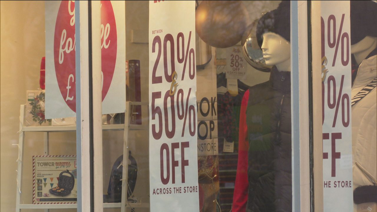 Discount signs are seen in the window of a shop.