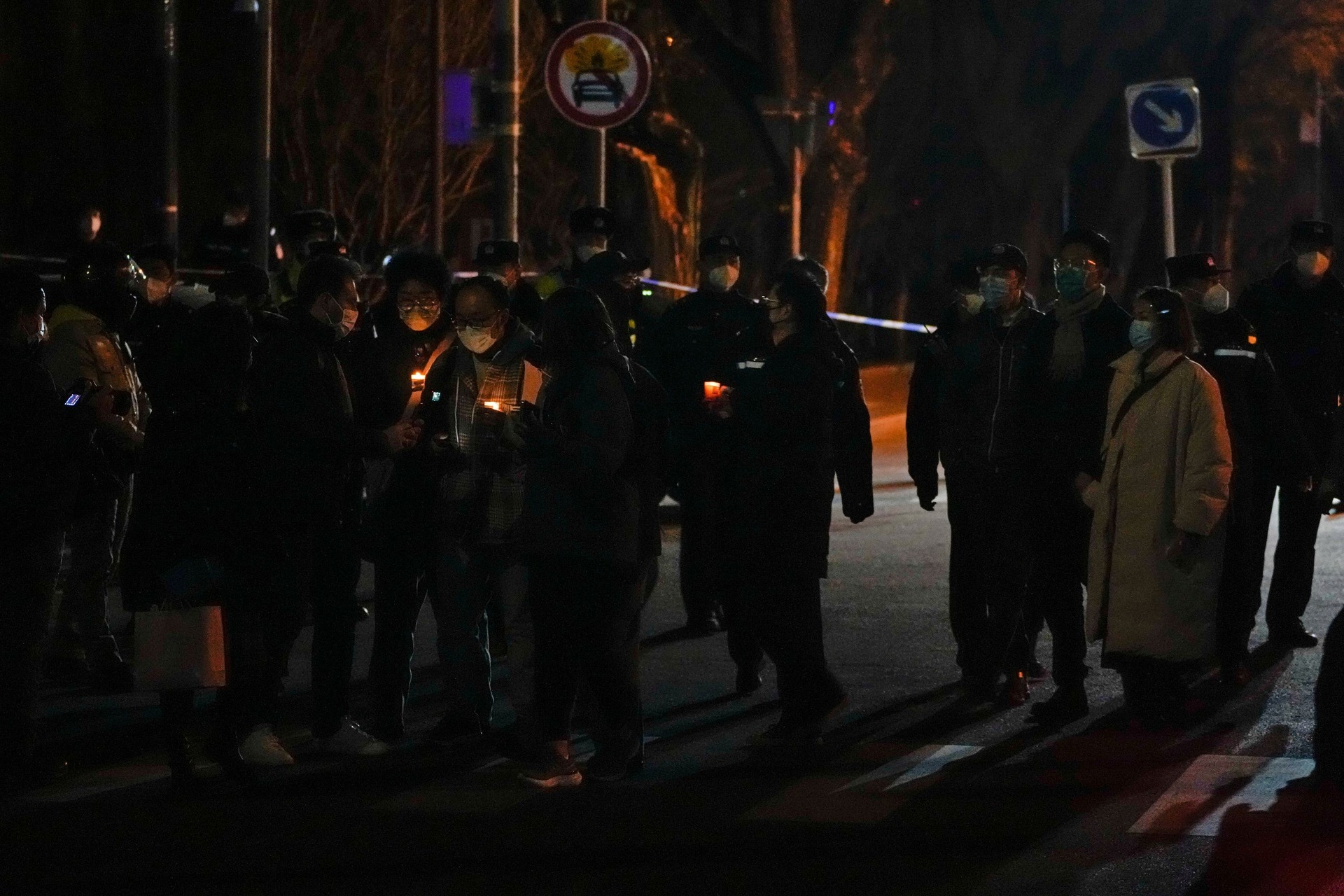 A group of protesters light candles near a police road block during a protest in Beijing (AP)
