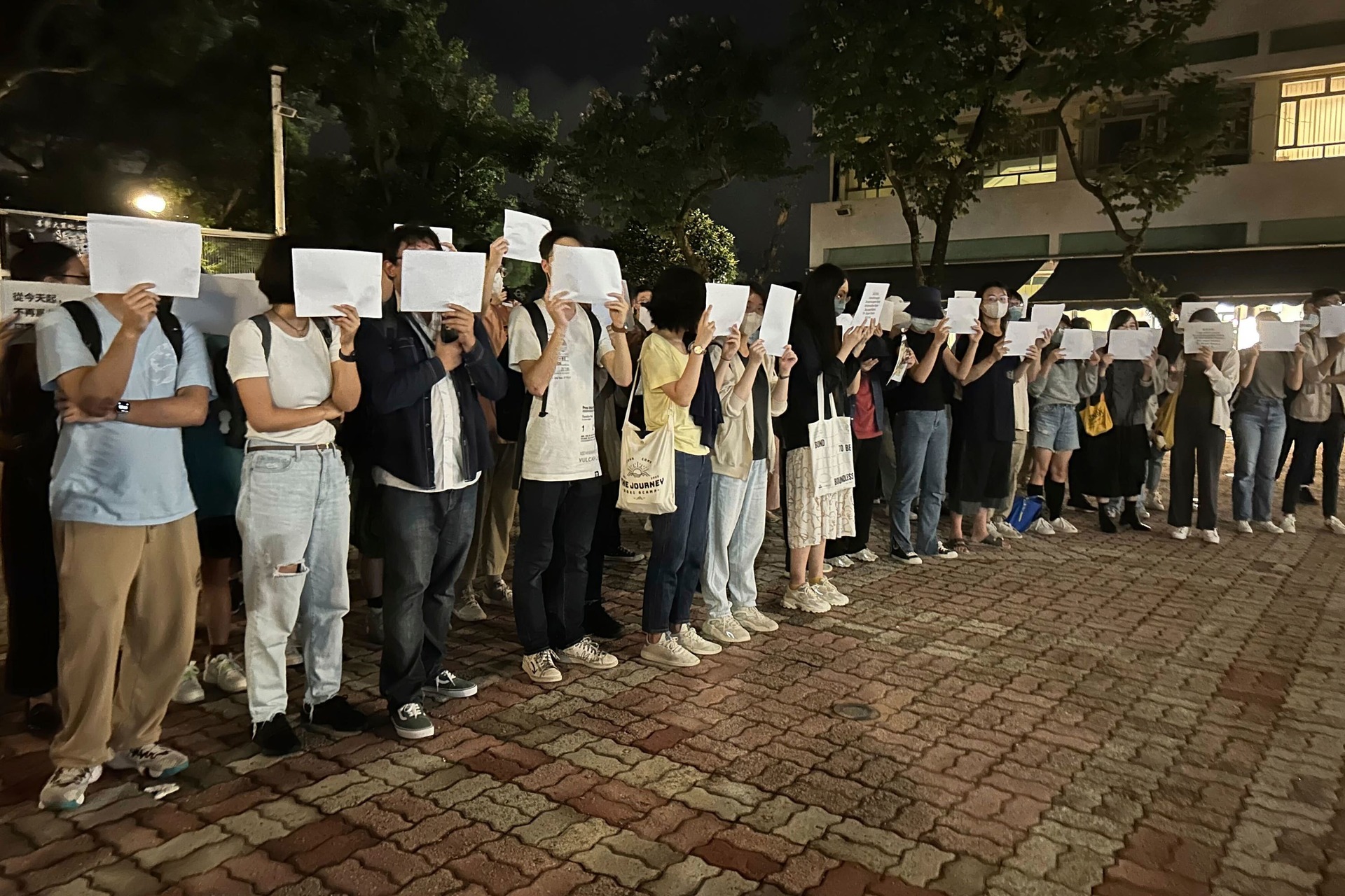 Protesters hold up blank white papers during a commemoration for victims of a recent Urumqi deadly fire at the Chinese University of Hong Kong in Hong Kong on Monday (Kanis Leung/AP)