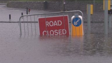 A road closed sign is seen half submerged on a flooded Edinburgh road