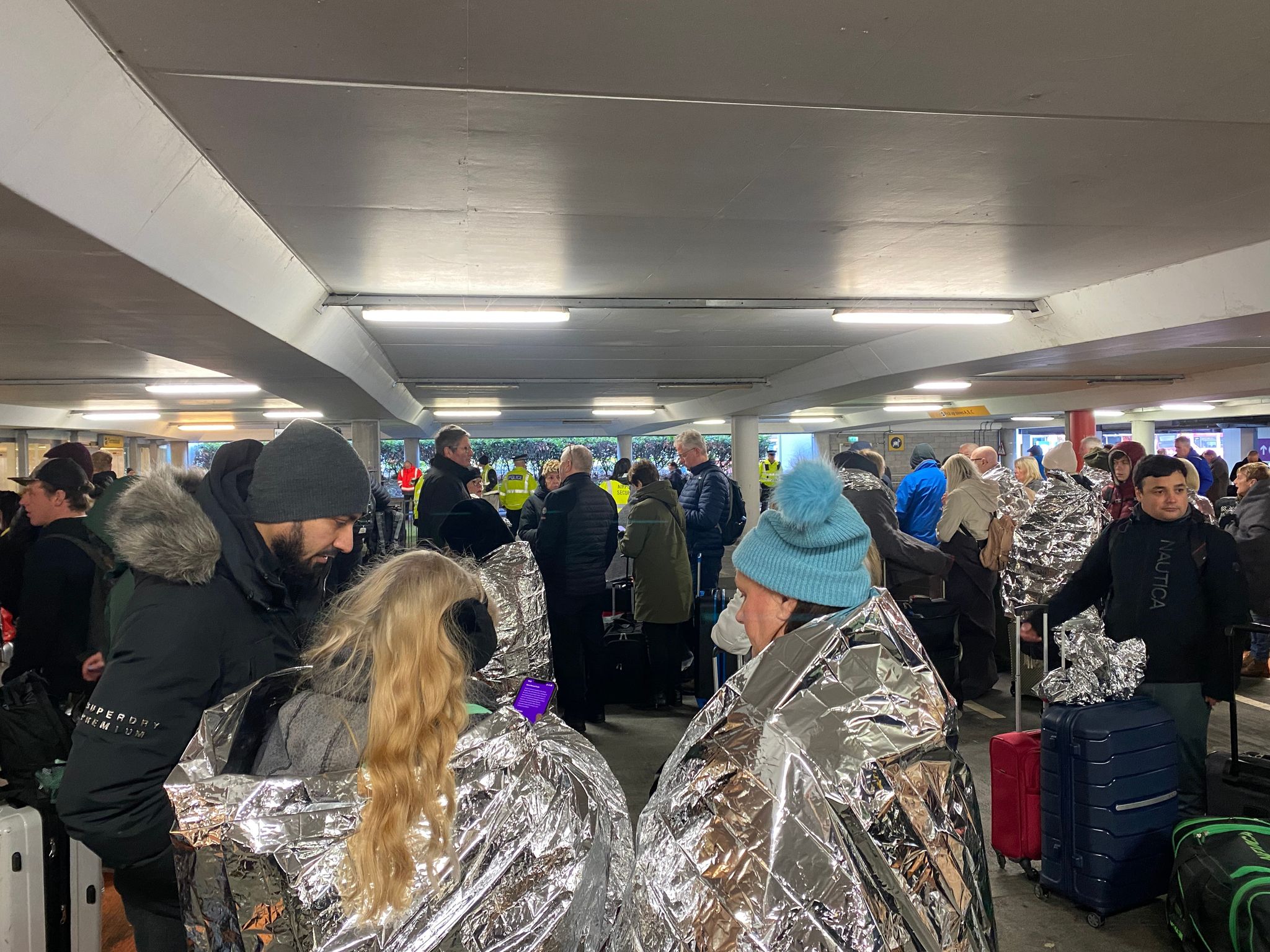 Cold and confused travellers gather in the airport's parking structure. 