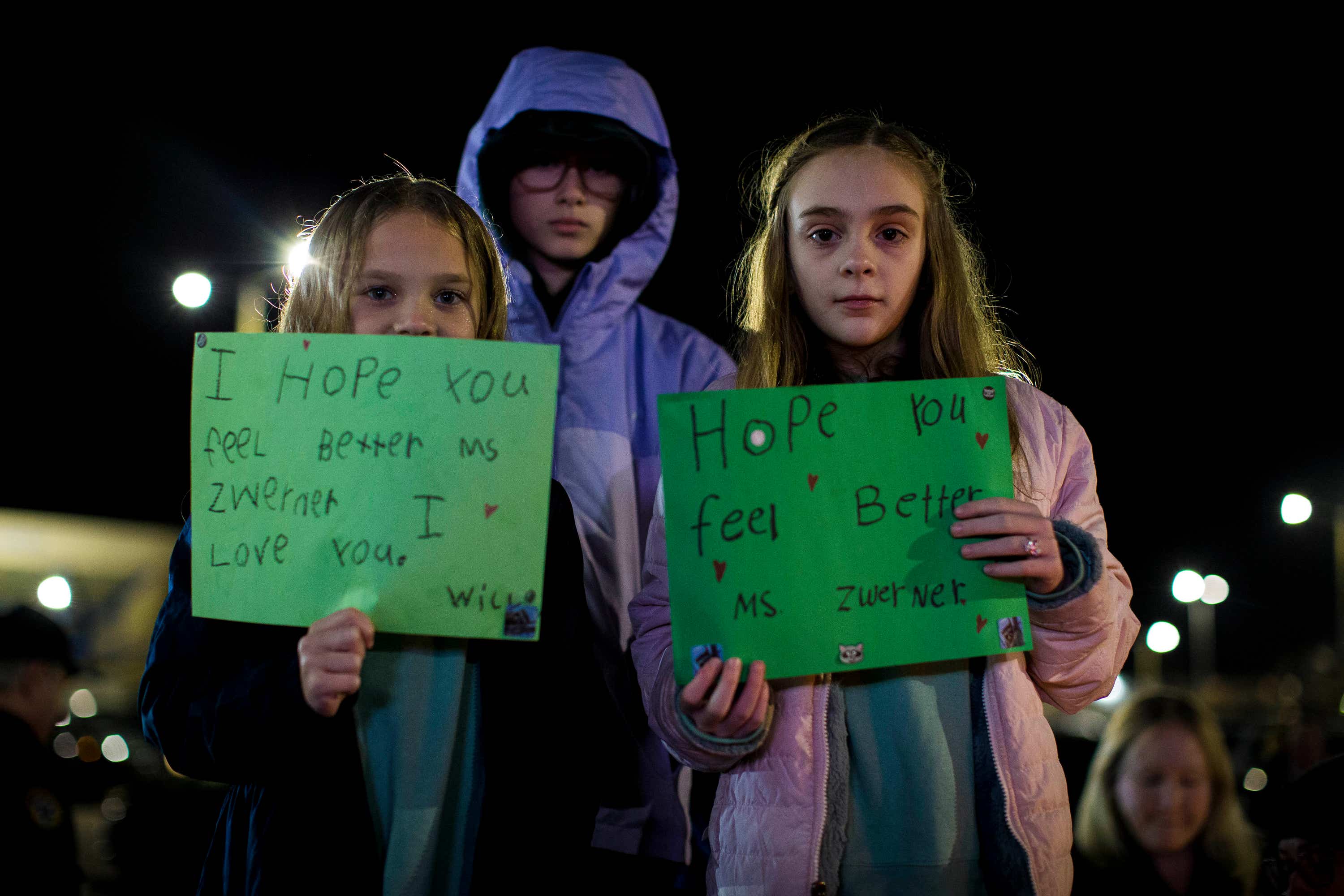 Willow Crawford, left, and her older sister Ava, right, join friend Kaylynn Vestre in expressing their support for Ms Zwerner during a candlelight vigil.
