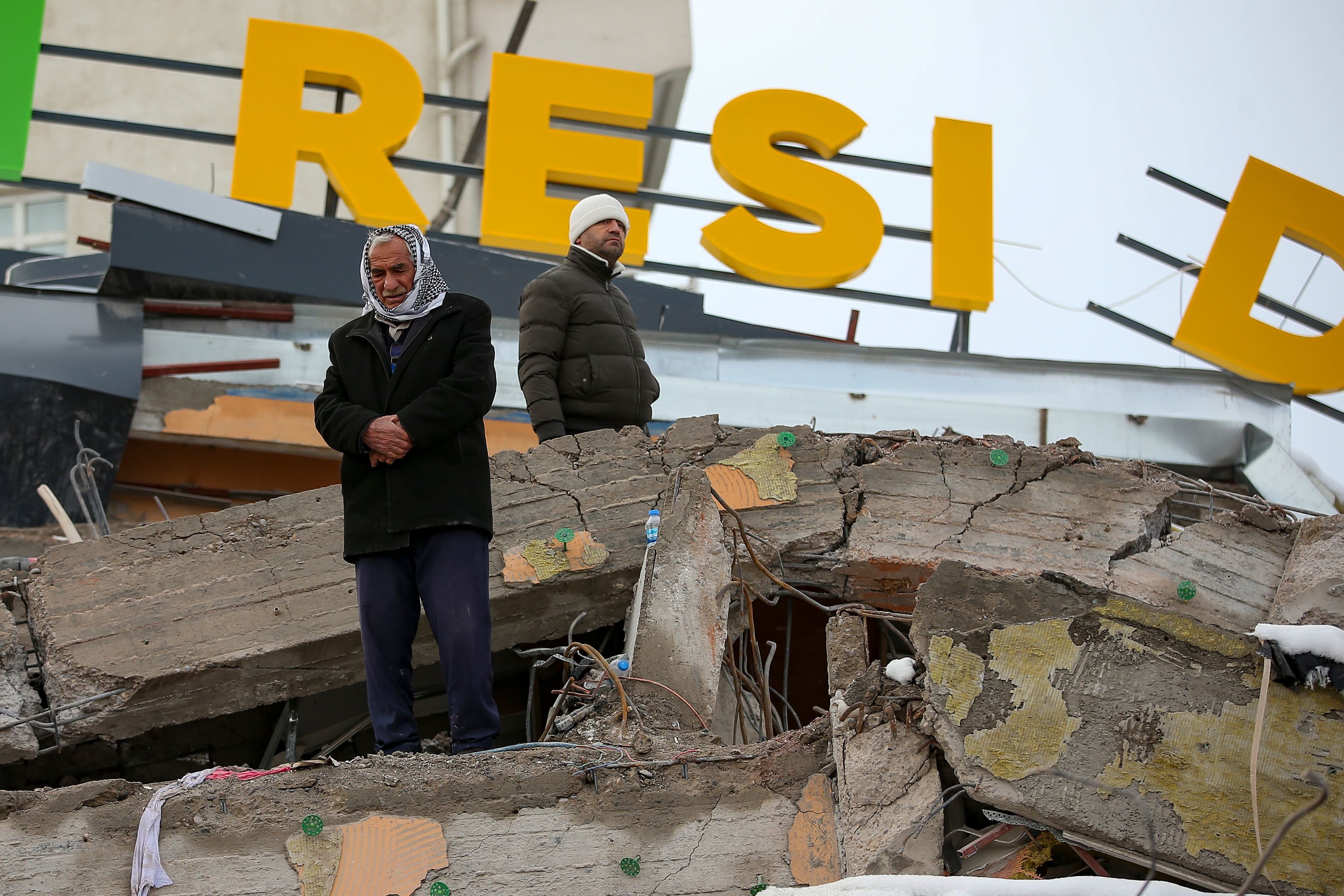 A man prays on a collapsed building in Malatya, Turkey (Emrah Gurel/AP)