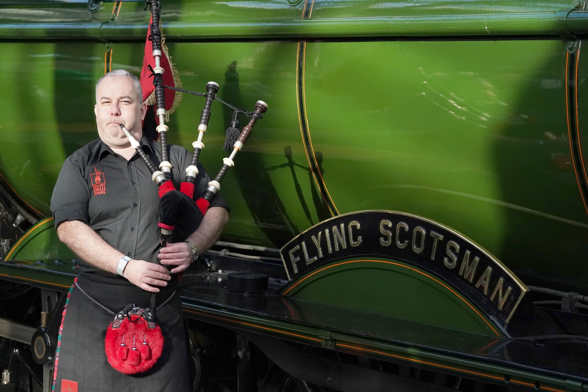 Kevin MacDonald from the Red Hot Chilli Pipers performed beside the famous locomotive (Andrew Milligan/PA) 