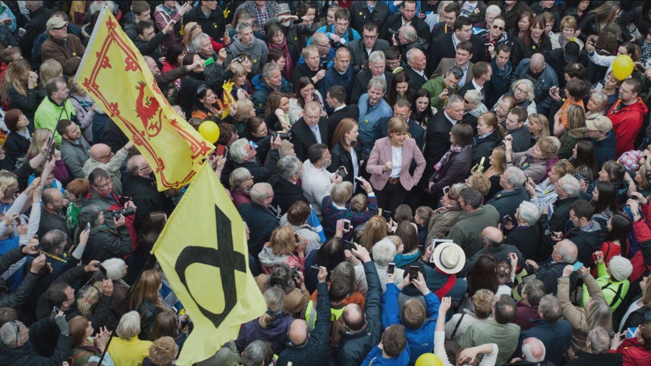 large crowd is seen from birds eye view, holding SNP and Scotland flags