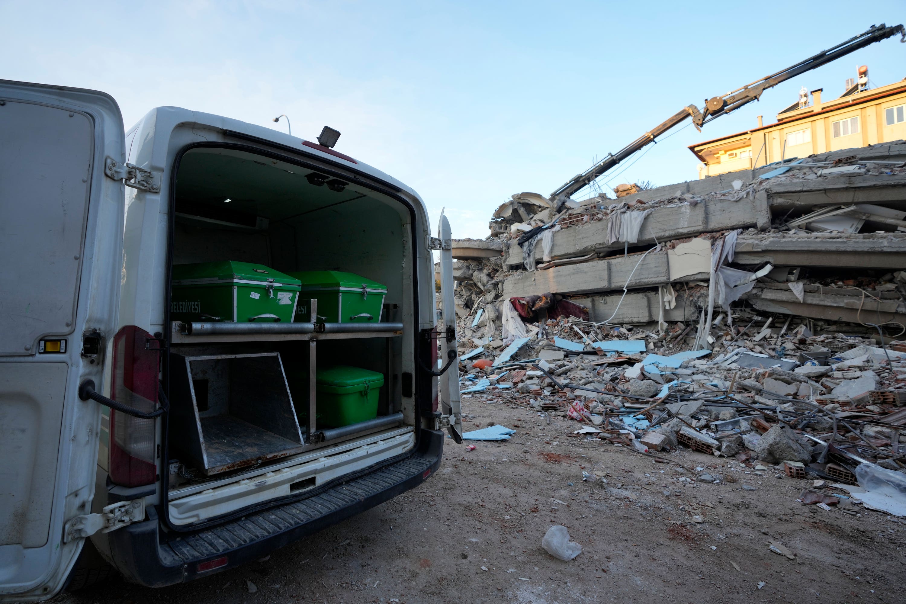  van with coffins is parked next to a destroyed building in Gaziantep, south-east Turkey (Kamran Jebreili/AP)