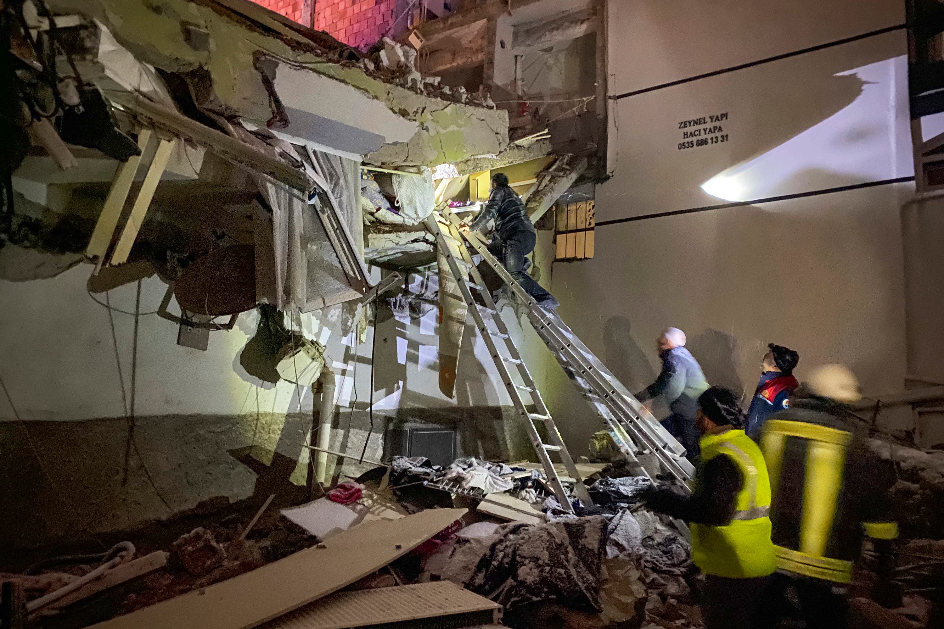 Rescue teams try to reach trapped residents inside collapsed buildings in Adana, Turkey (IHA agency via AP)
