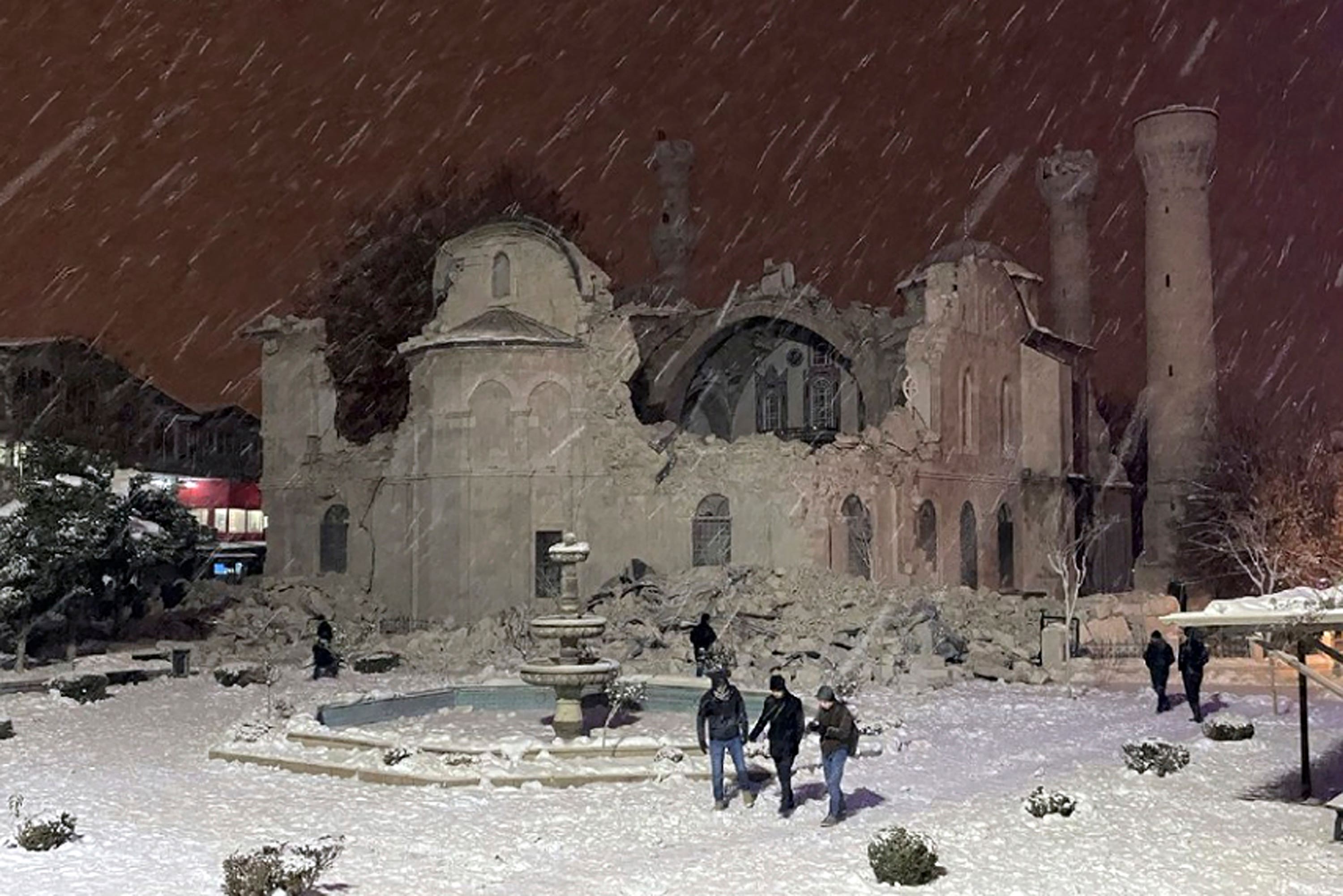 People walk next to a mosque destroyed by the quake in Malatya, Turkey (DIA via AP)
