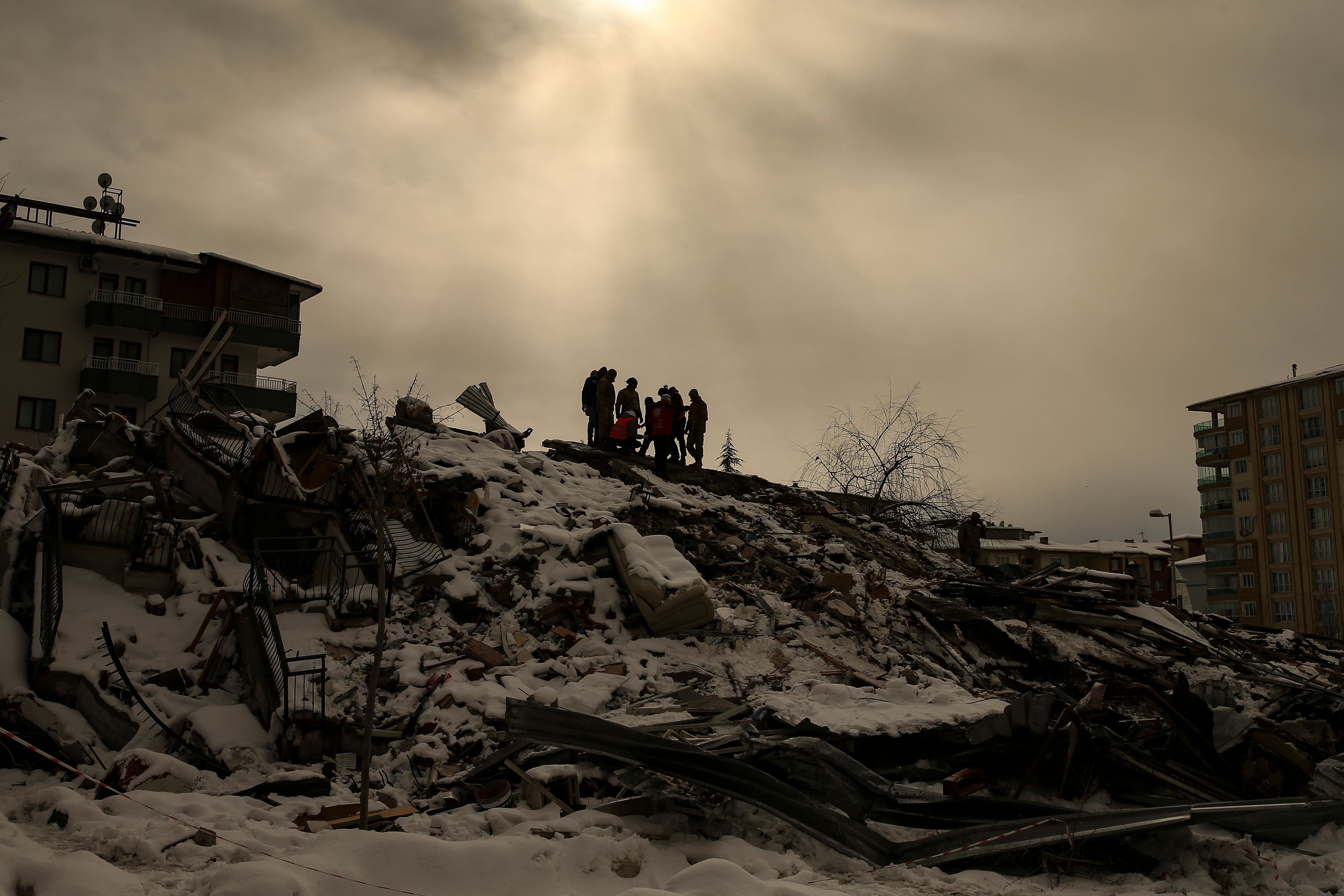 People try to reach people trapped under the debris of a collapsed building in Malatya, Turkey (Emrah Gurel/AP)
