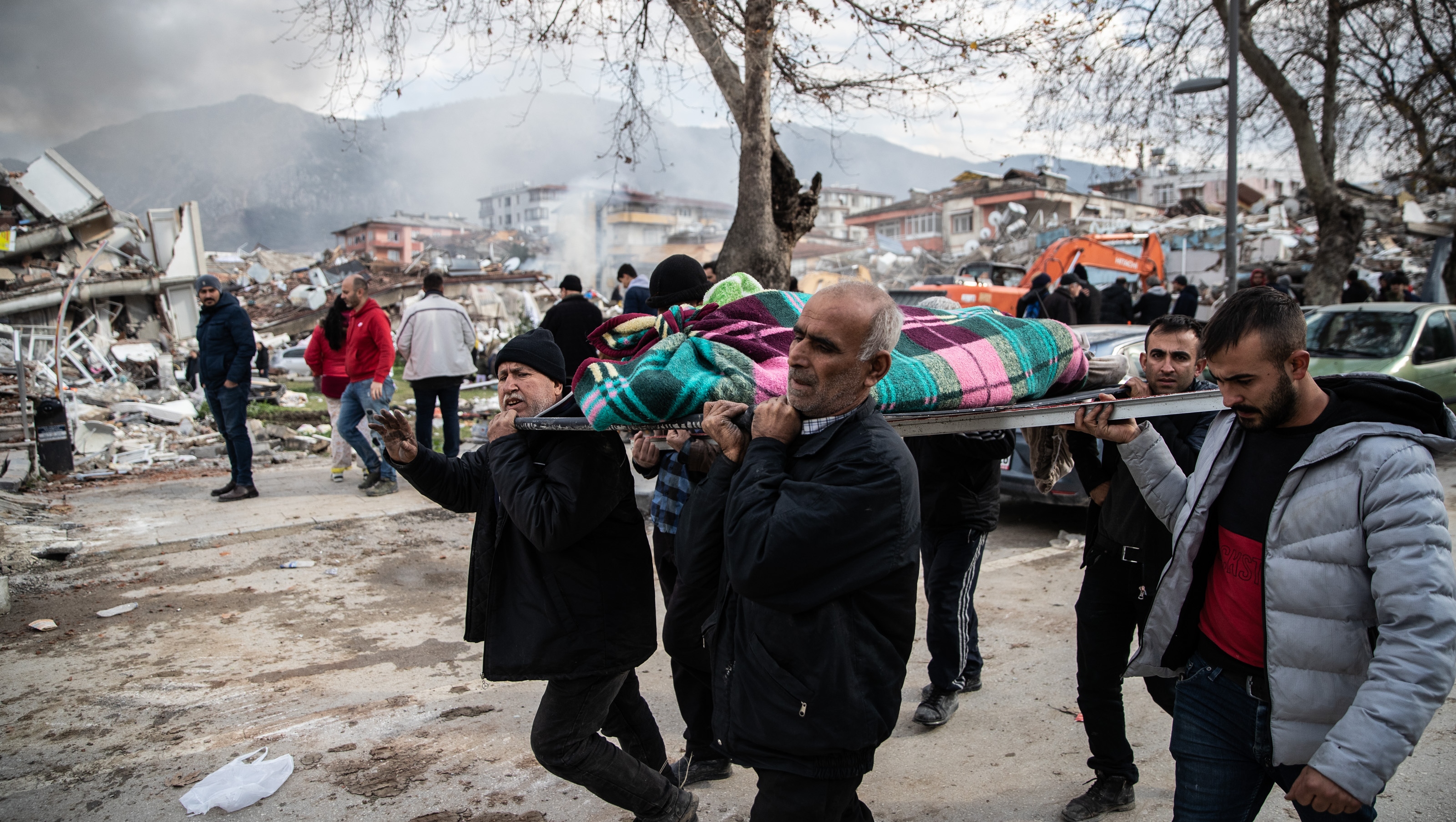 People carry a dead body near the collapsed buildings on February 06, 2023 in Hata, Turkey.