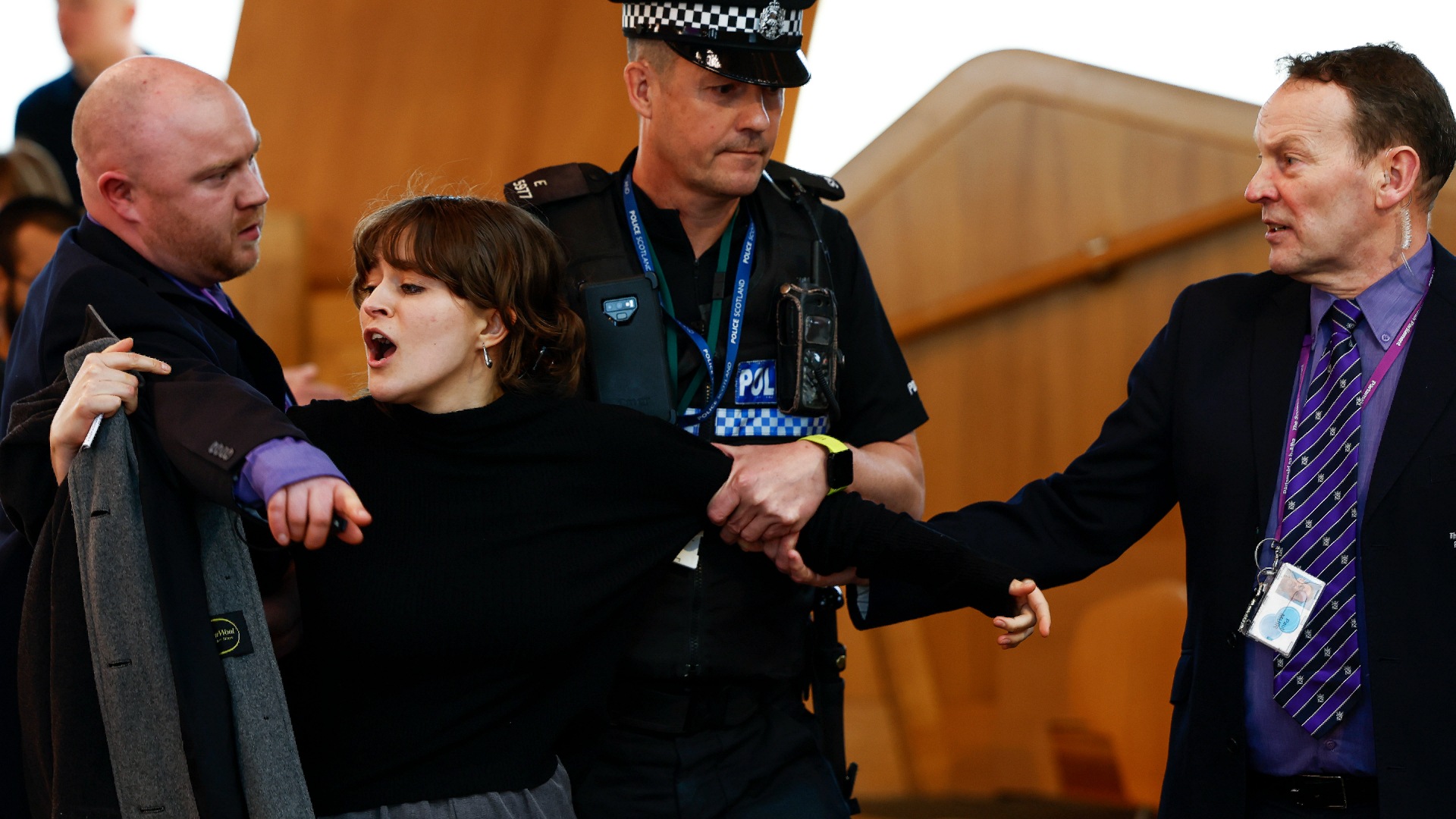 Police and security staff escort a protester from the public gallery during First Minister's Questions.