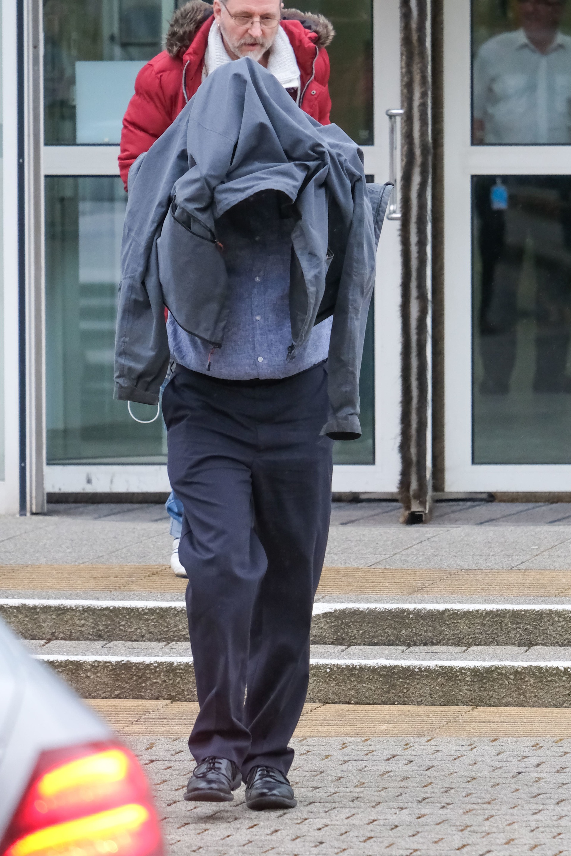 Timothy Schofield covers his head as he leaves Exeter Crown Court.