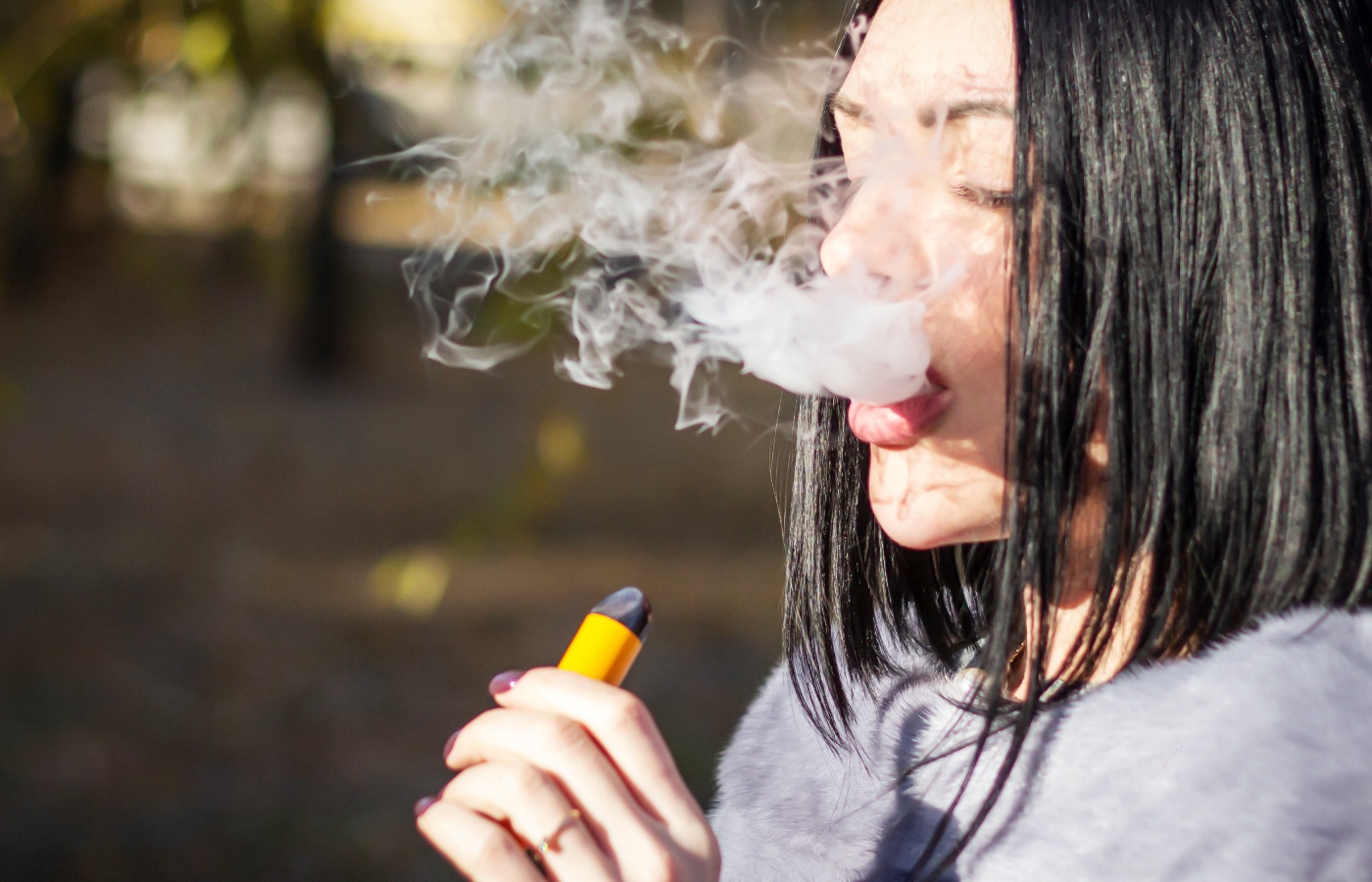 The girl smokes an electronic cigarette on the street.
vape vaping teenage