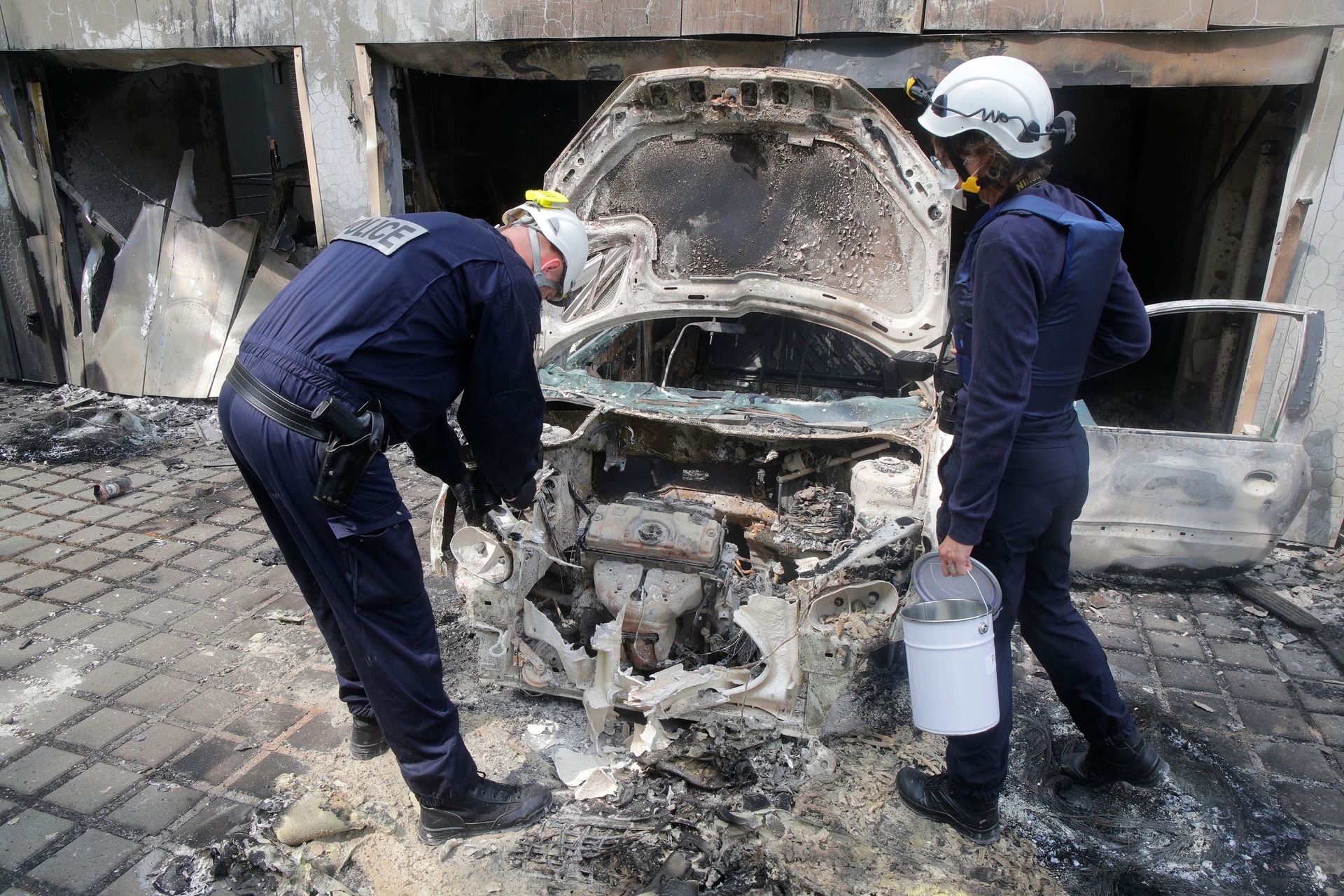 Police officers work on a charred car at the city hall of Mons-en-Barœul, northern France Thursday.