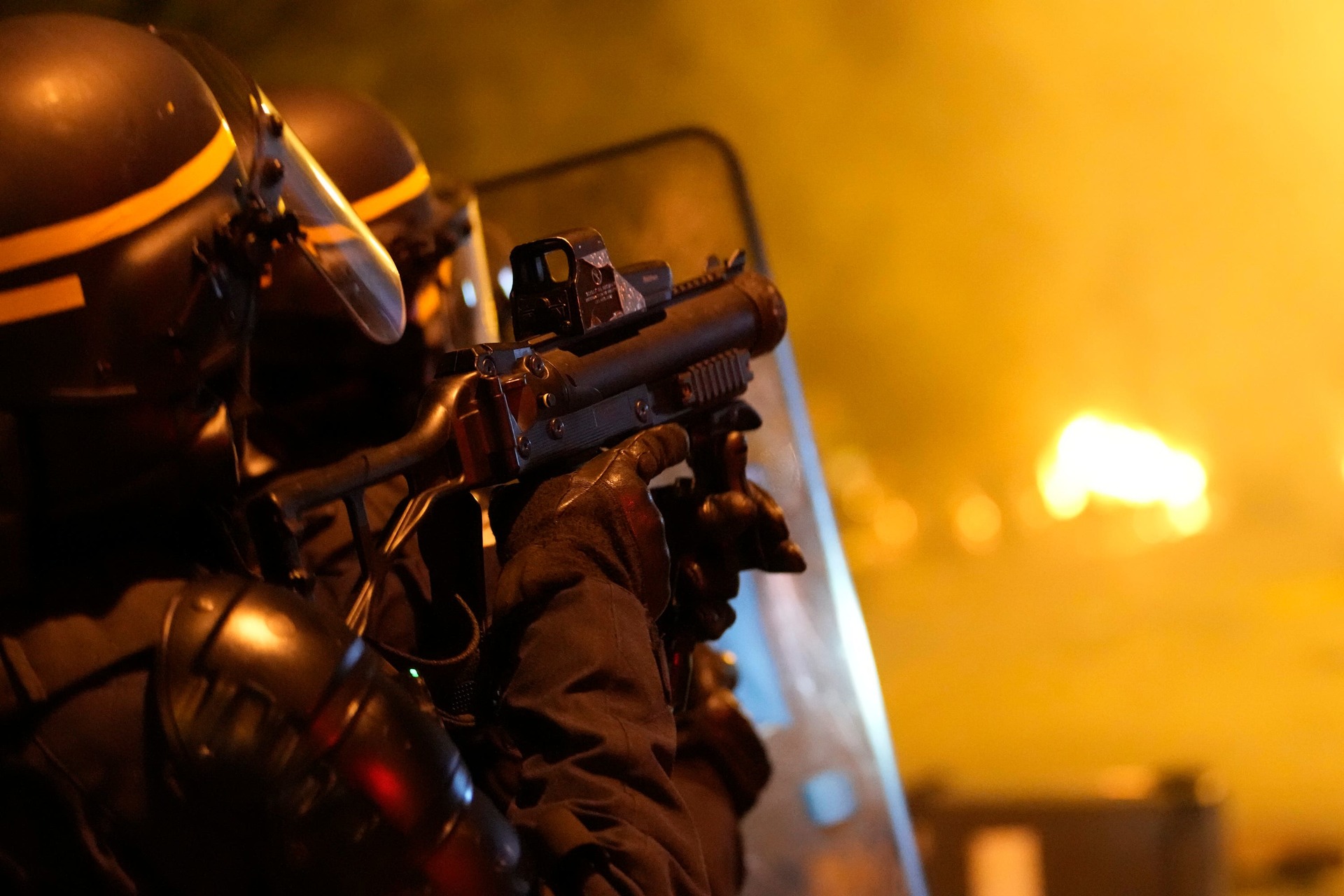 A police officer fires tear gas during clashes with youths in Nanterre .