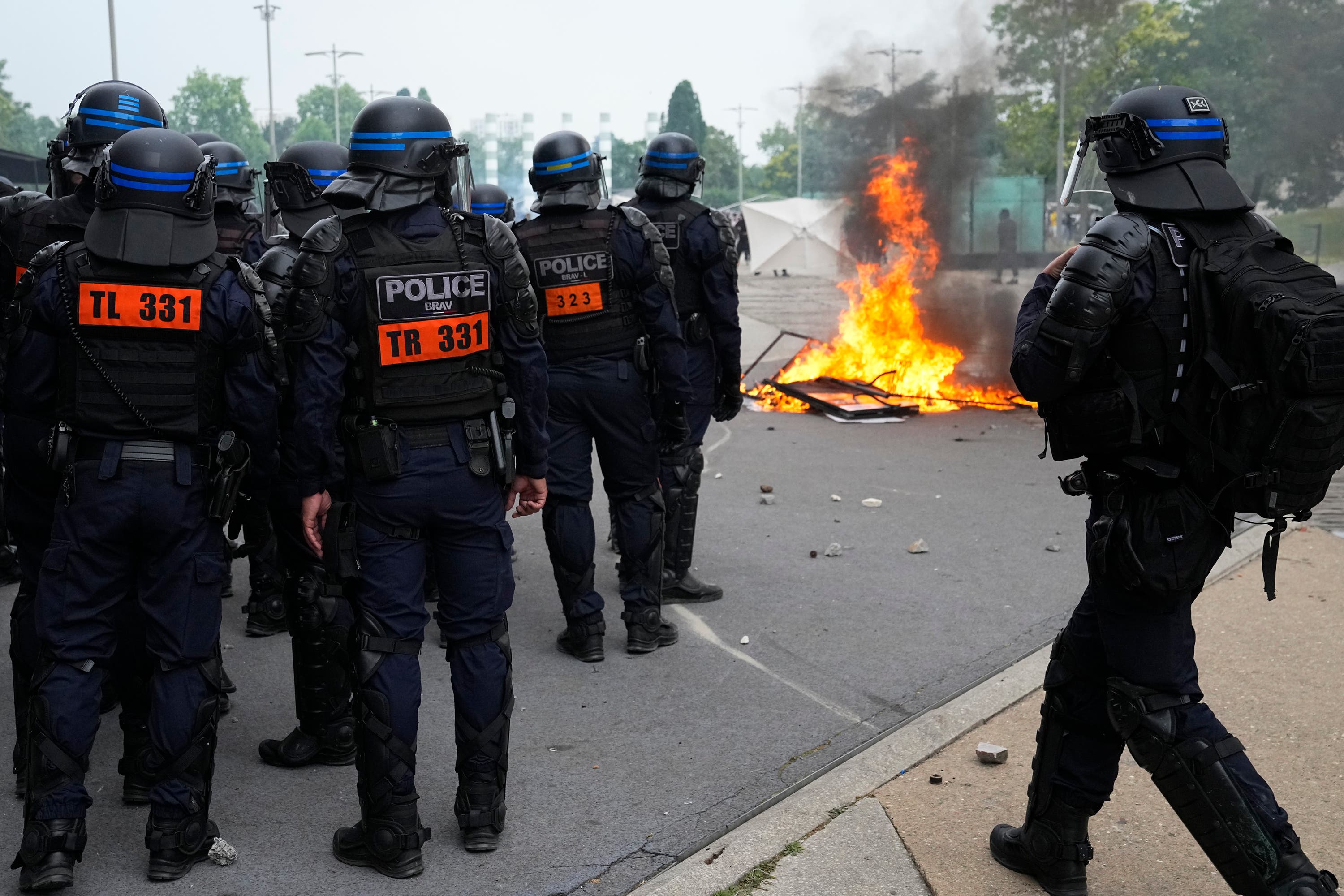 Riot police officers stand by a fire after a march for Nahel in Nanterre.