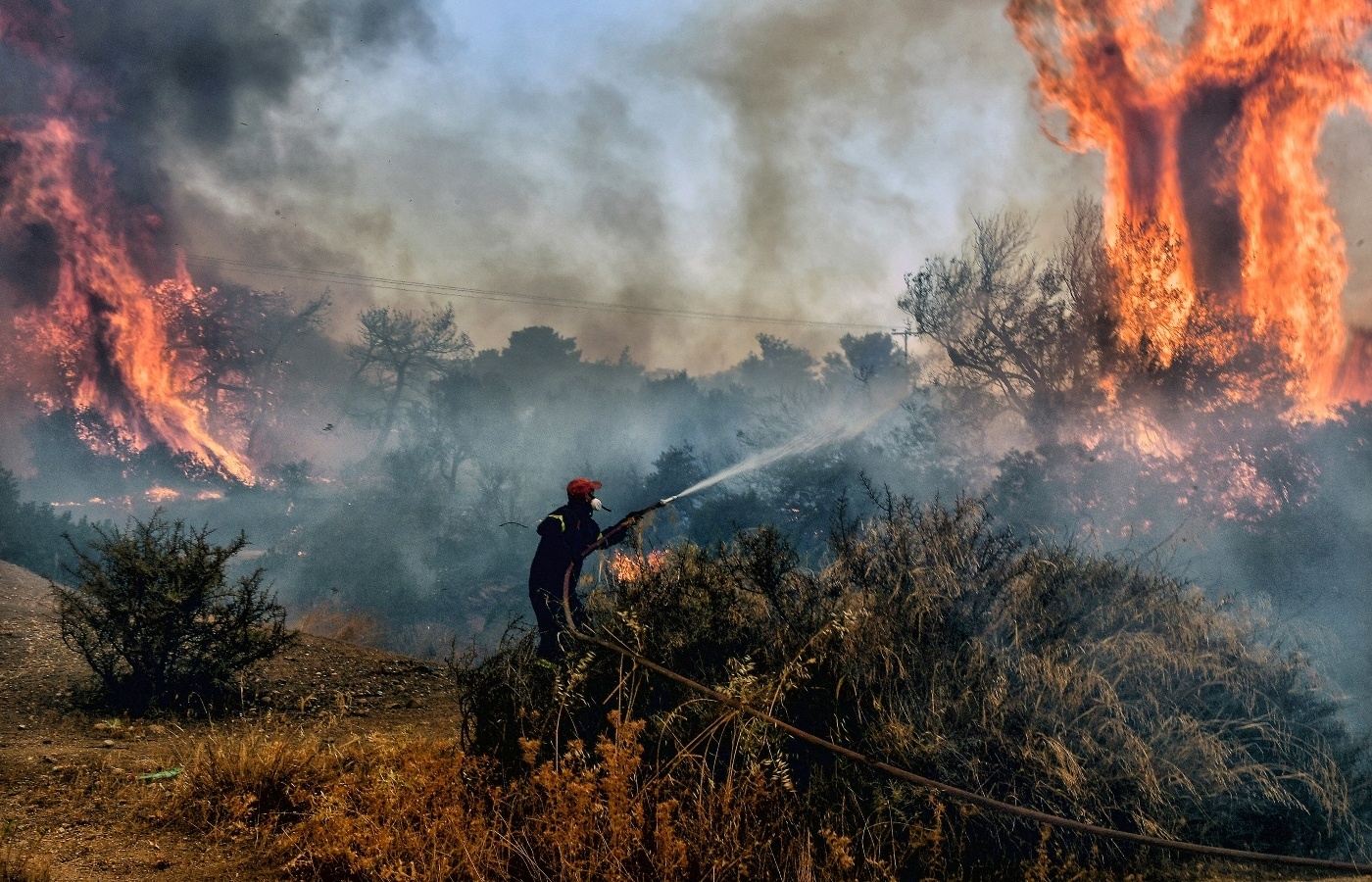 A fireman douses flames on a wildfire in Greece. 