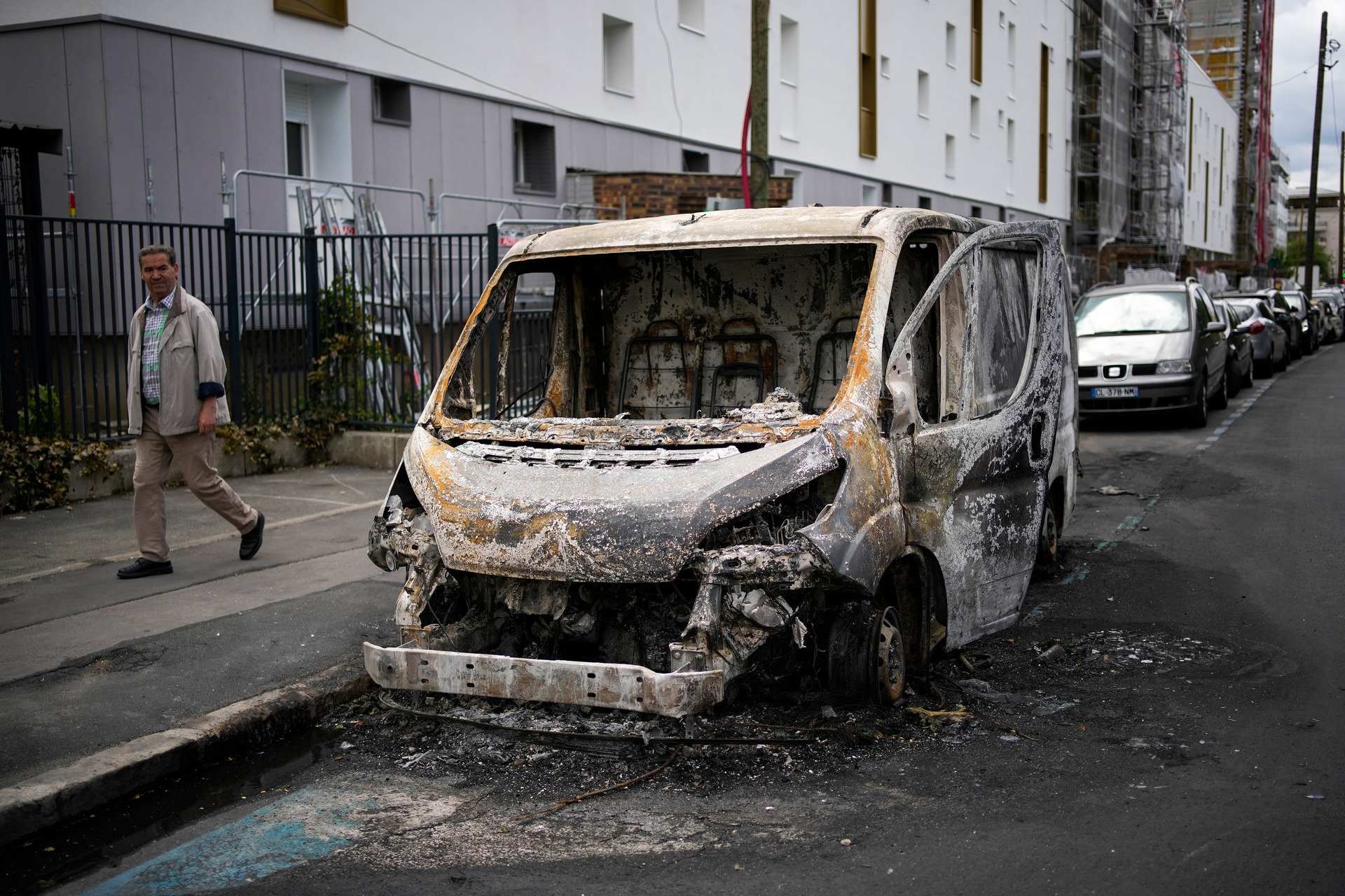 A man walks past a burned van in the aftermath of protests in Colombes, outside Paris.