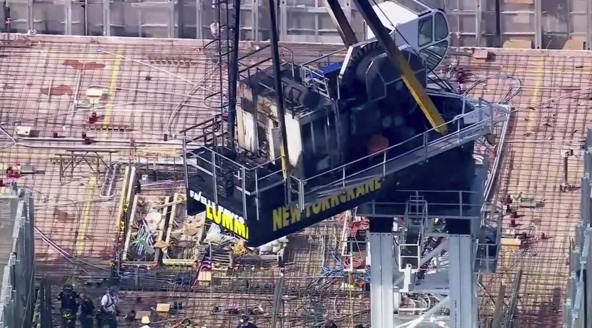 Emergency responders are on the scene after a large construction crane caught fire in Manhattan on Wednesday, July 26, 2023 in New York.   The crane caught fire and its arm hit a building as it crashed to the street below.  (WABC via AP)