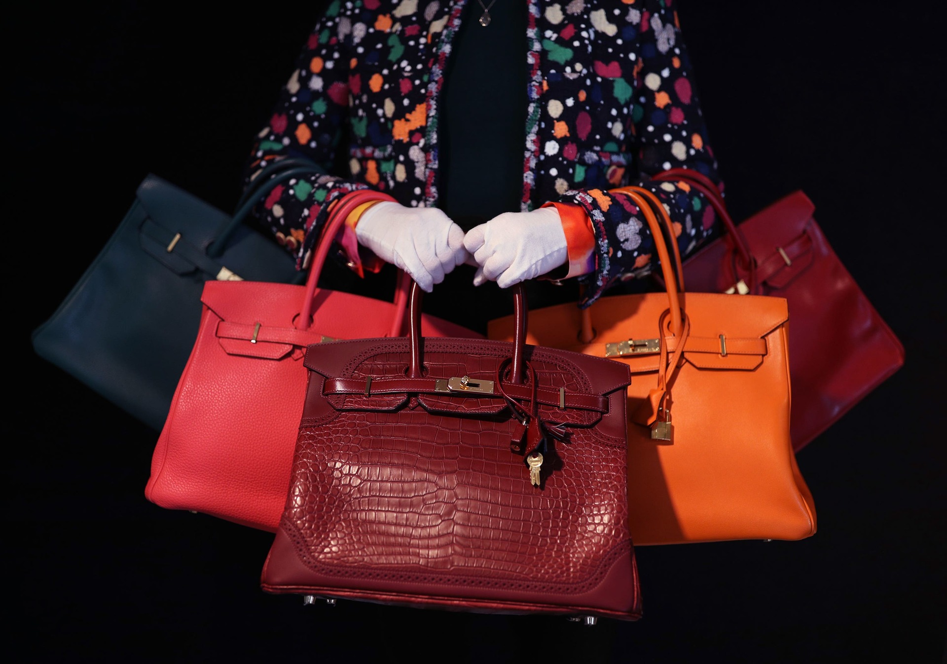 Meg Randell, Head of Designer Handbags and Fashion at Bonhams, holding a range of Birkin bag