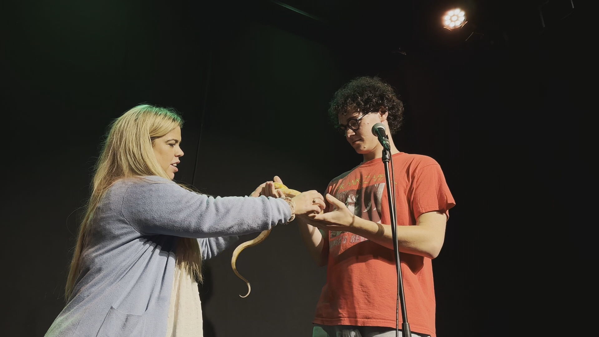 Danielle assisting Charlie on stage with a snake during his comedy set. 