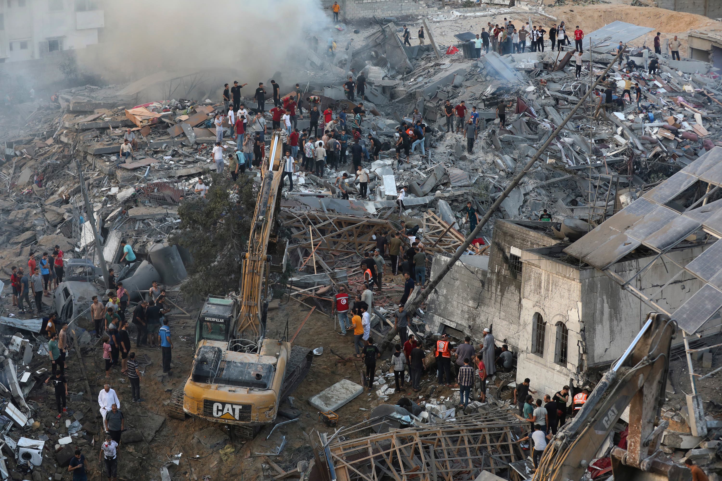 Palestinians inspect the damage of destroyed buildings following Israeli airstrikes on Gaza City.
