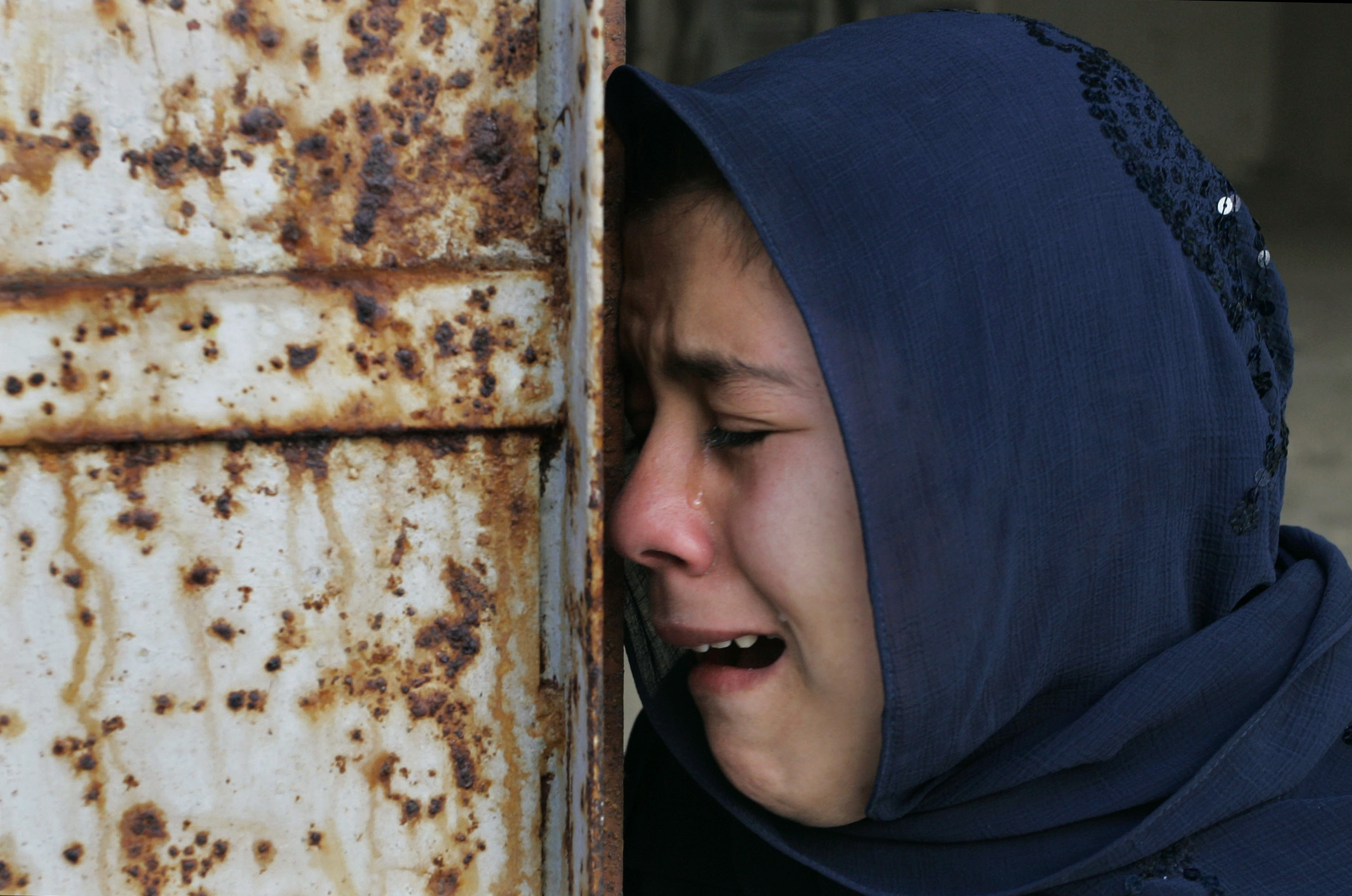 A Palestinian woman who had 10 relatives killed near a United Nations school, weeps during their funeral.