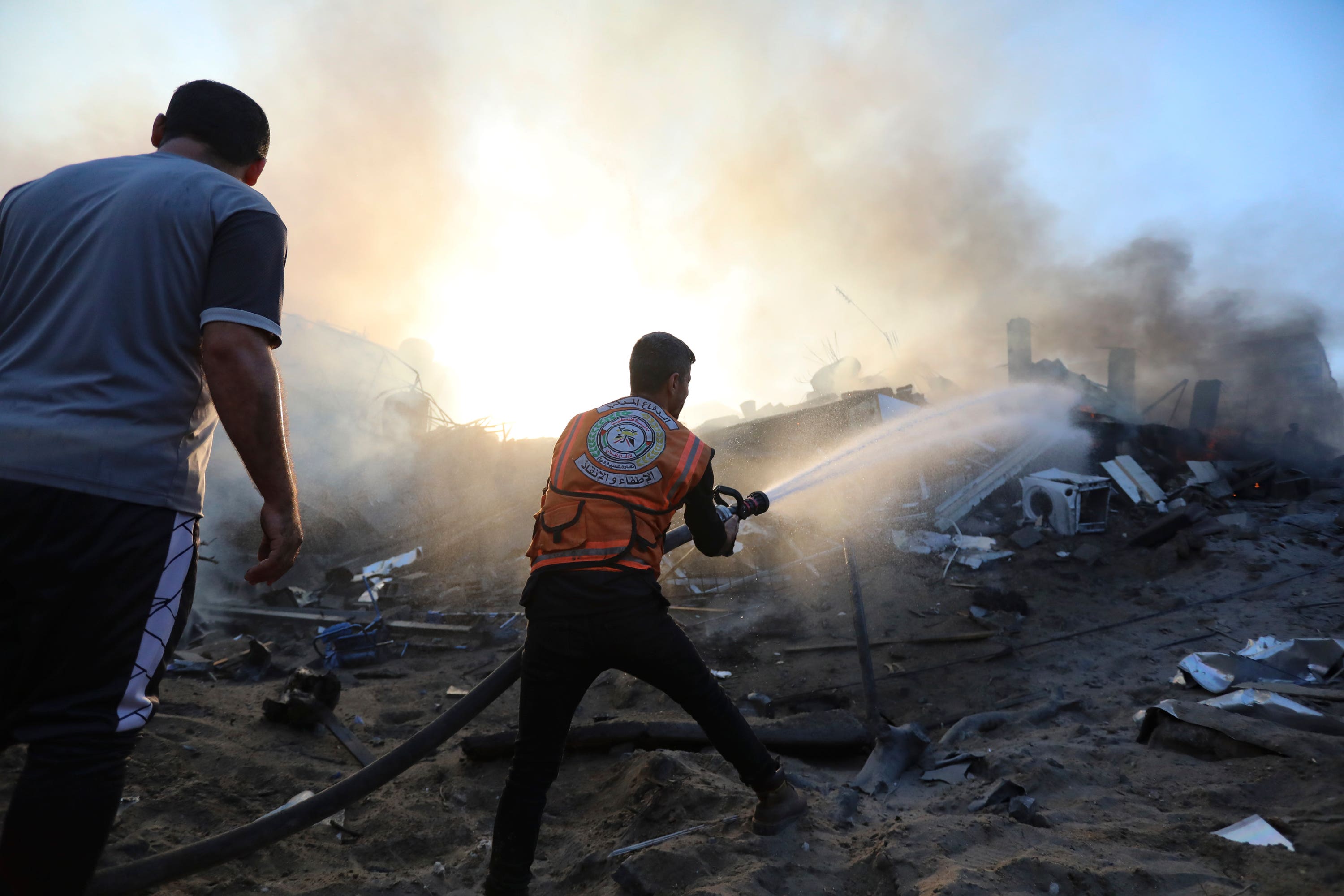 A Palestinian firefighter extinguishes a fire in a destroyed building following Israeli airstrikes on Gaza City.