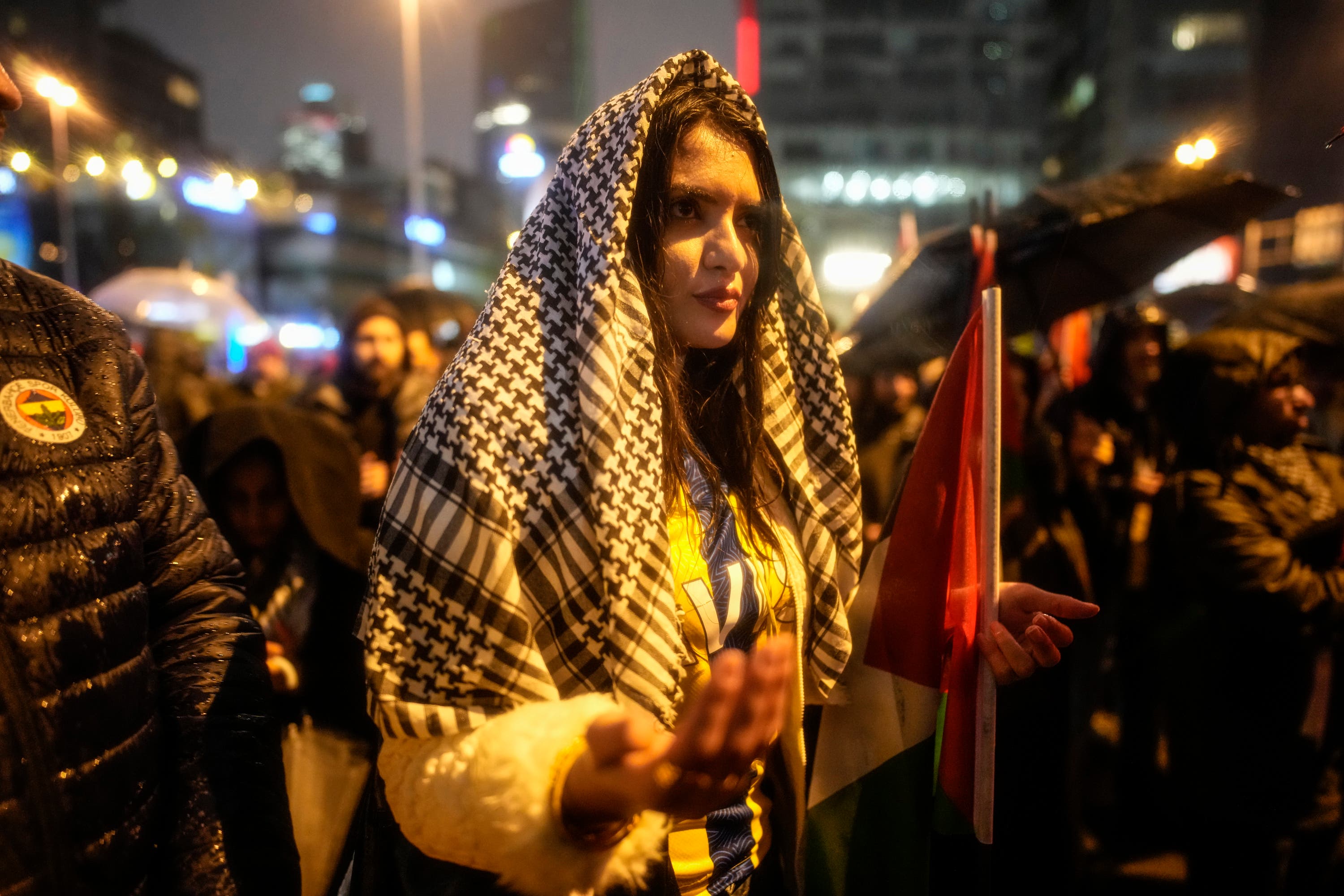 A woman prays during heavy rain during a pro-Palestinian protest outside the Israeli consulate in Istanbul on Saturday.
