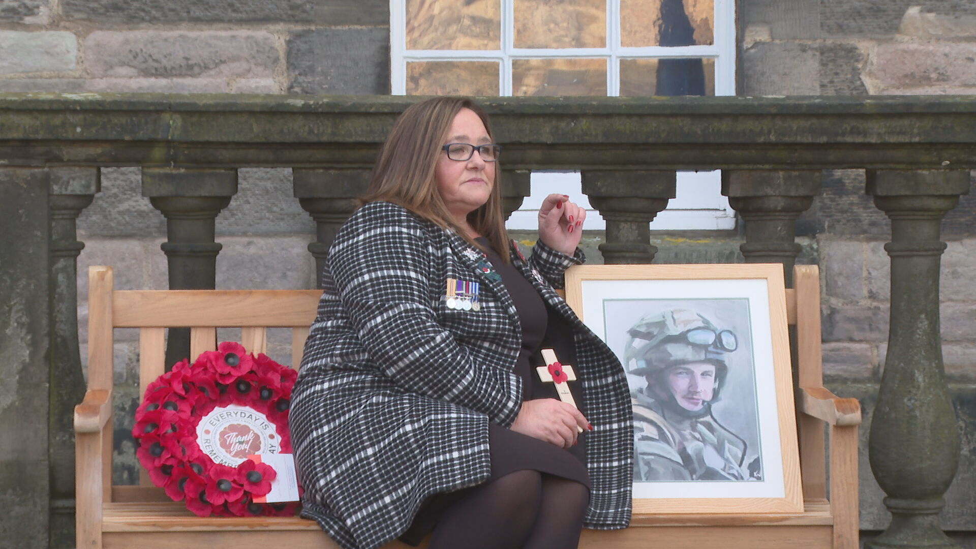 Janette Binnie sitting on the bench next to a painting of her son, Sergeant Sean Binnie, who died in Afghanistan.