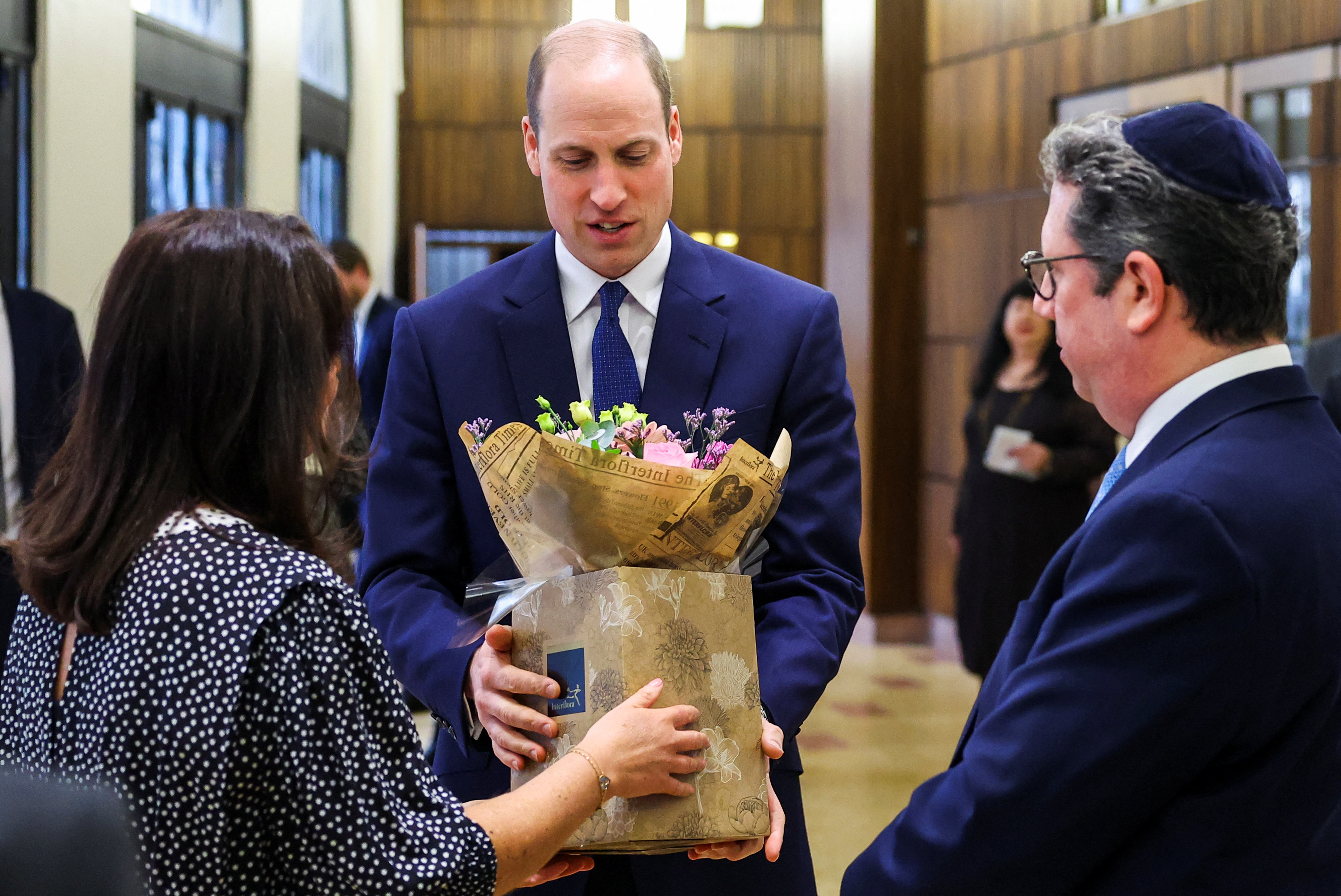 LONDON, ENGLAND - FEBRUARY 29: Britain's Prince William, Prince of Wales speaks receives a bouquet of flowers for his wife Catherine, Princess of Wales during a visit to the Western Marble Arch Synagogue on February 29, 2024 in London, England. (phot by Toby Melville - WPA Pool/Getty Images)