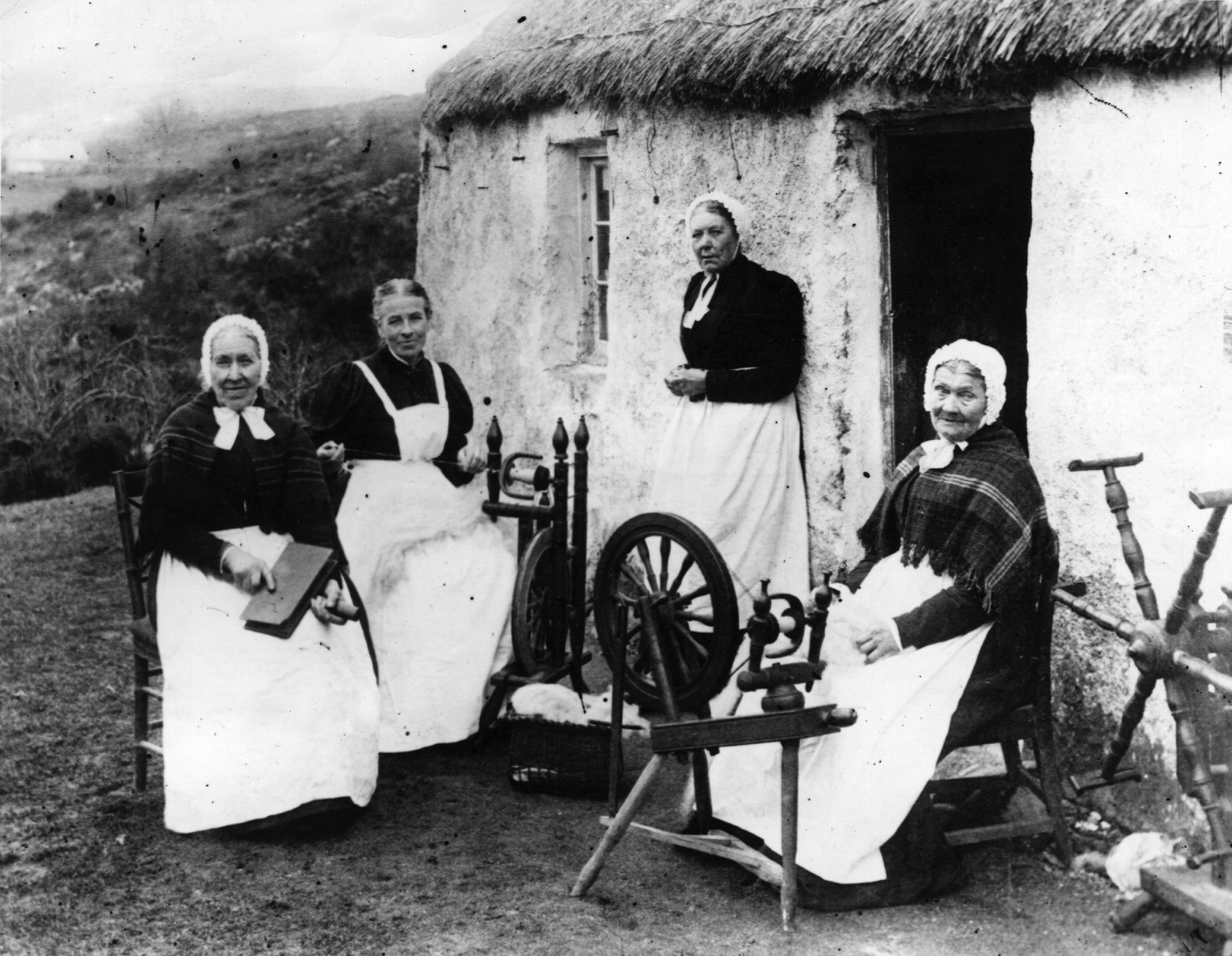 Circa 1909:  Scottish crofting women carding and spinning wool with their spinning wheels in the Highlands.  (Photo by Topical Press Agency/Getty Images)