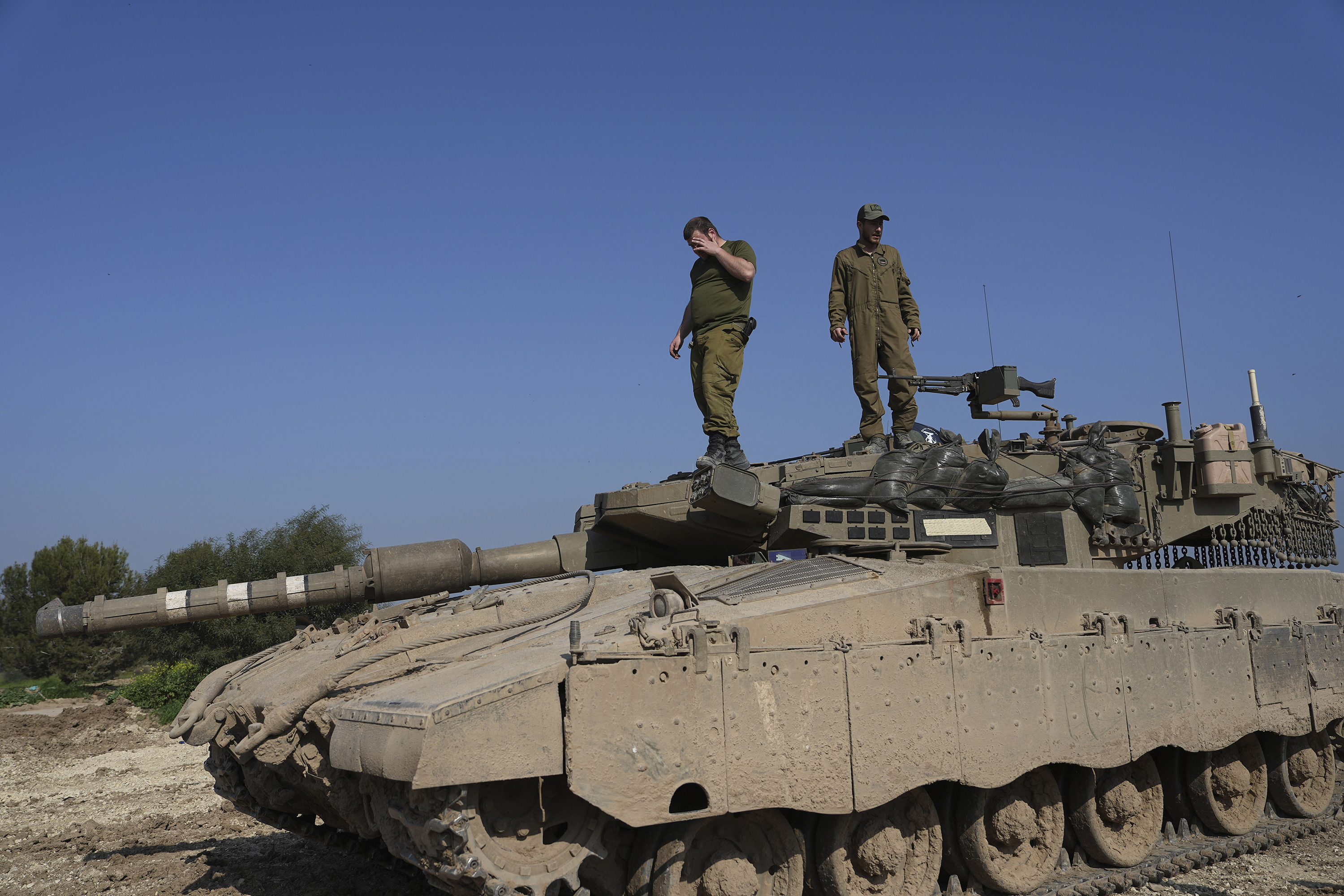 Israeli soldiers stand on their tank in a staging area near the Israel-Gaza border.