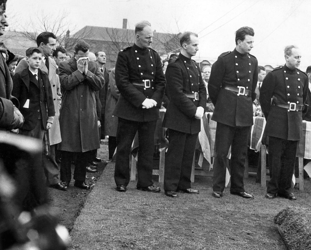 Firemen and relatives gather on 6th April 1960 for the funeral of a victim of the blaze.
